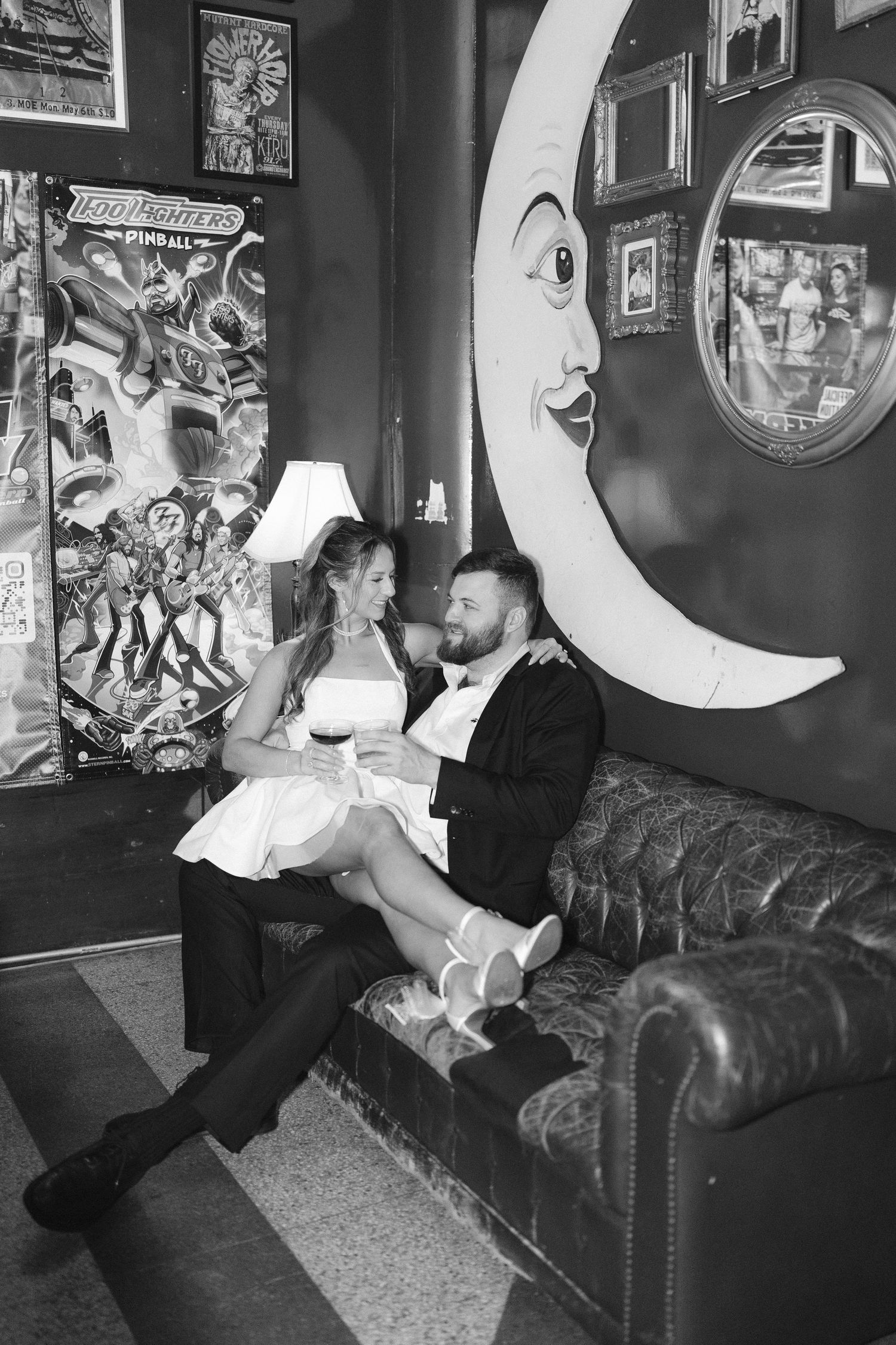 Black and white photo series showing a couple lounging on a vintage leather couch with decorative moon prop.