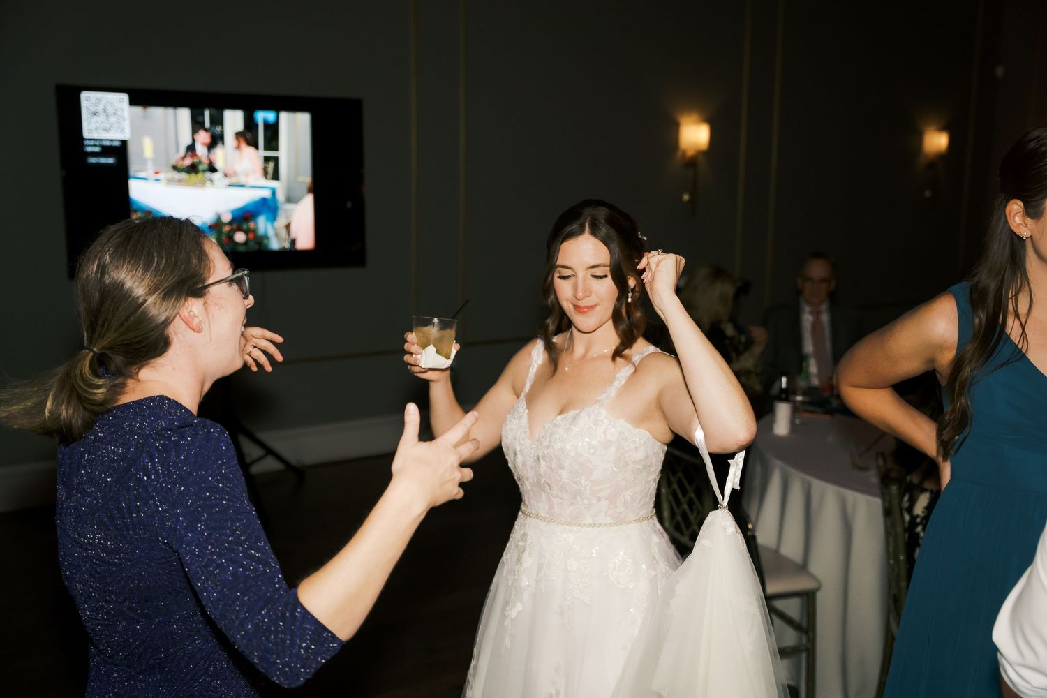 Wedding guests dancing and celebrating at a dimly lit indoor reception.