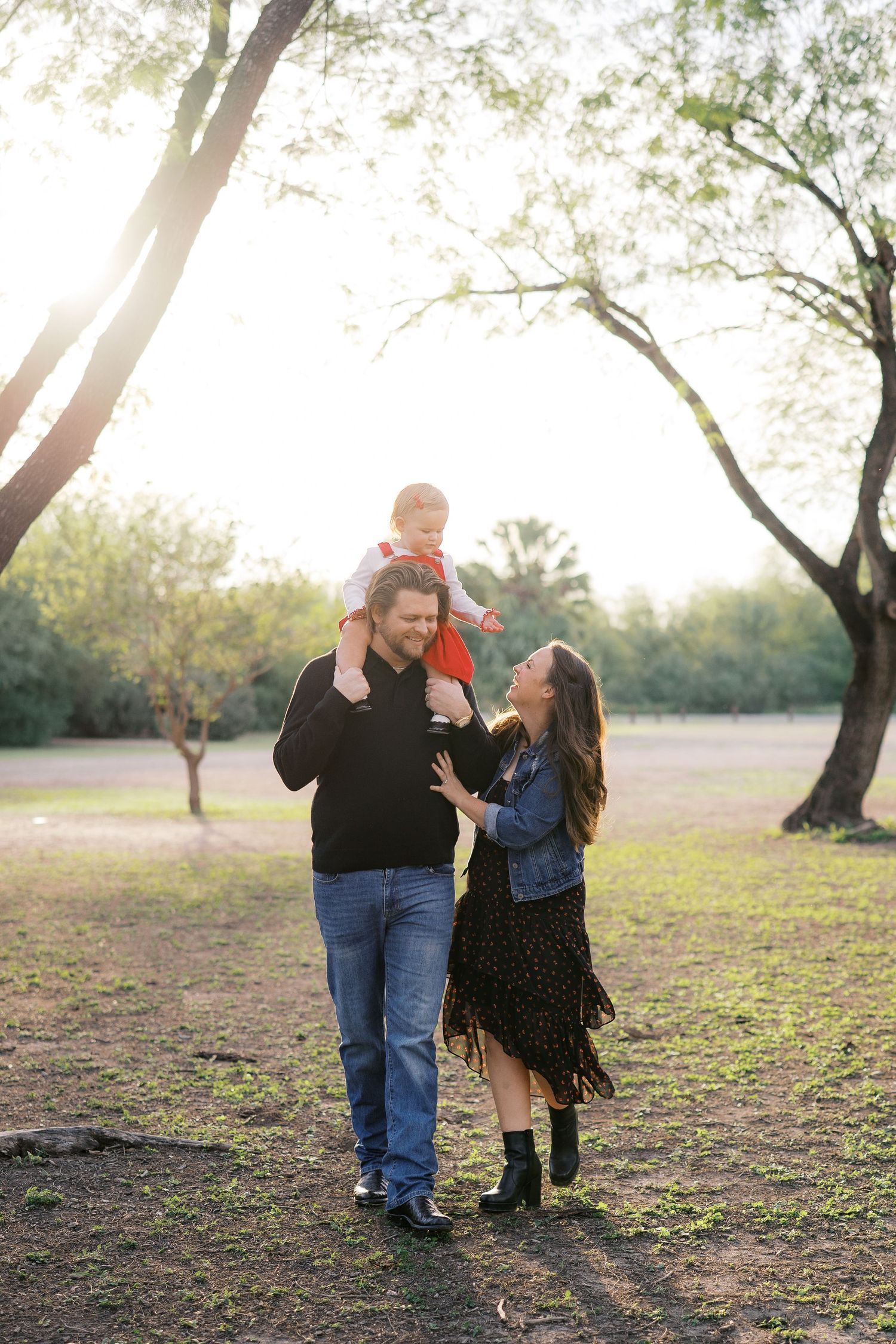 Family enjoying playful moments together in a park during sunset.