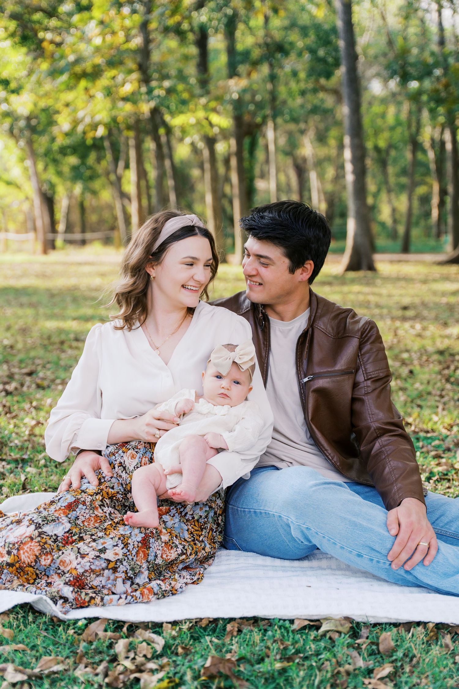 Family enjoys picnic on blanket in autumn park setting.