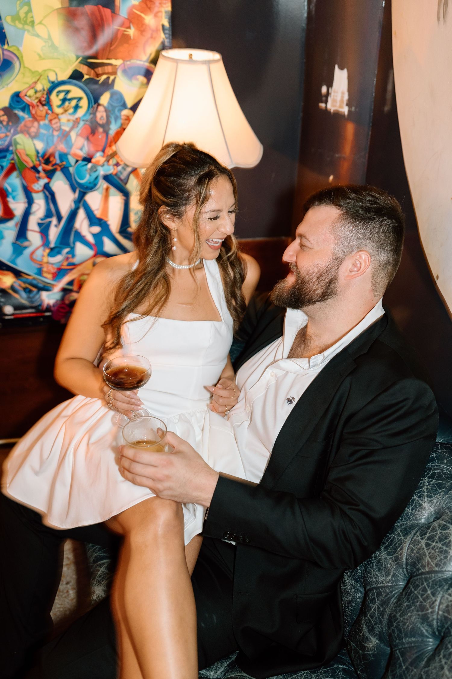 Romantic couple sharing playful moments on a vintage couch with ambient lighting.