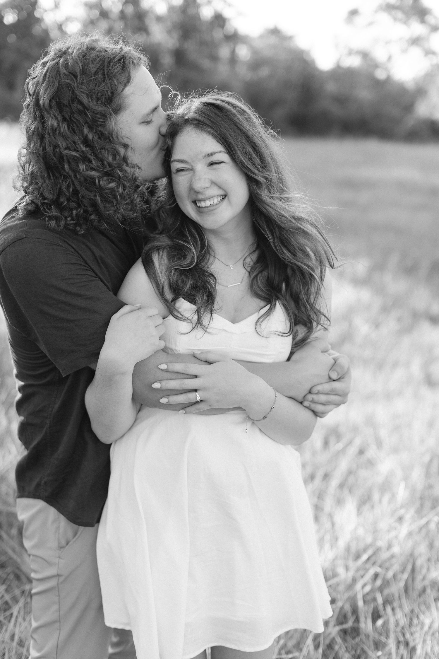 Couple sharing intimate moments in a field of tall grass in black and white.