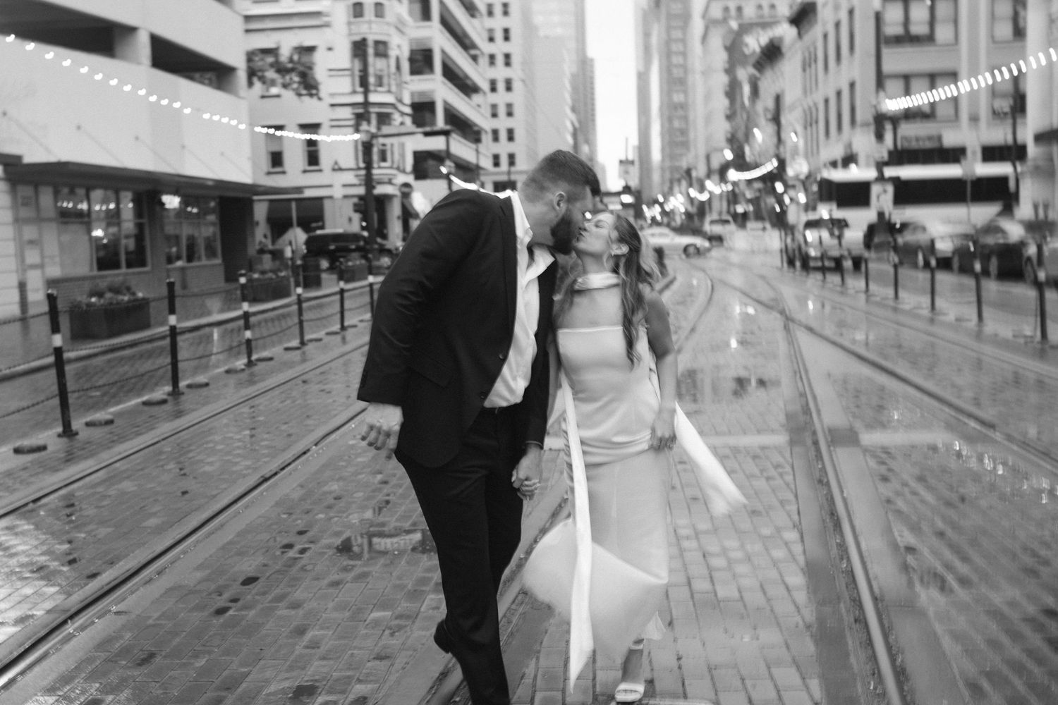 Couple walks through downtown street with historic buildings and train tracks.