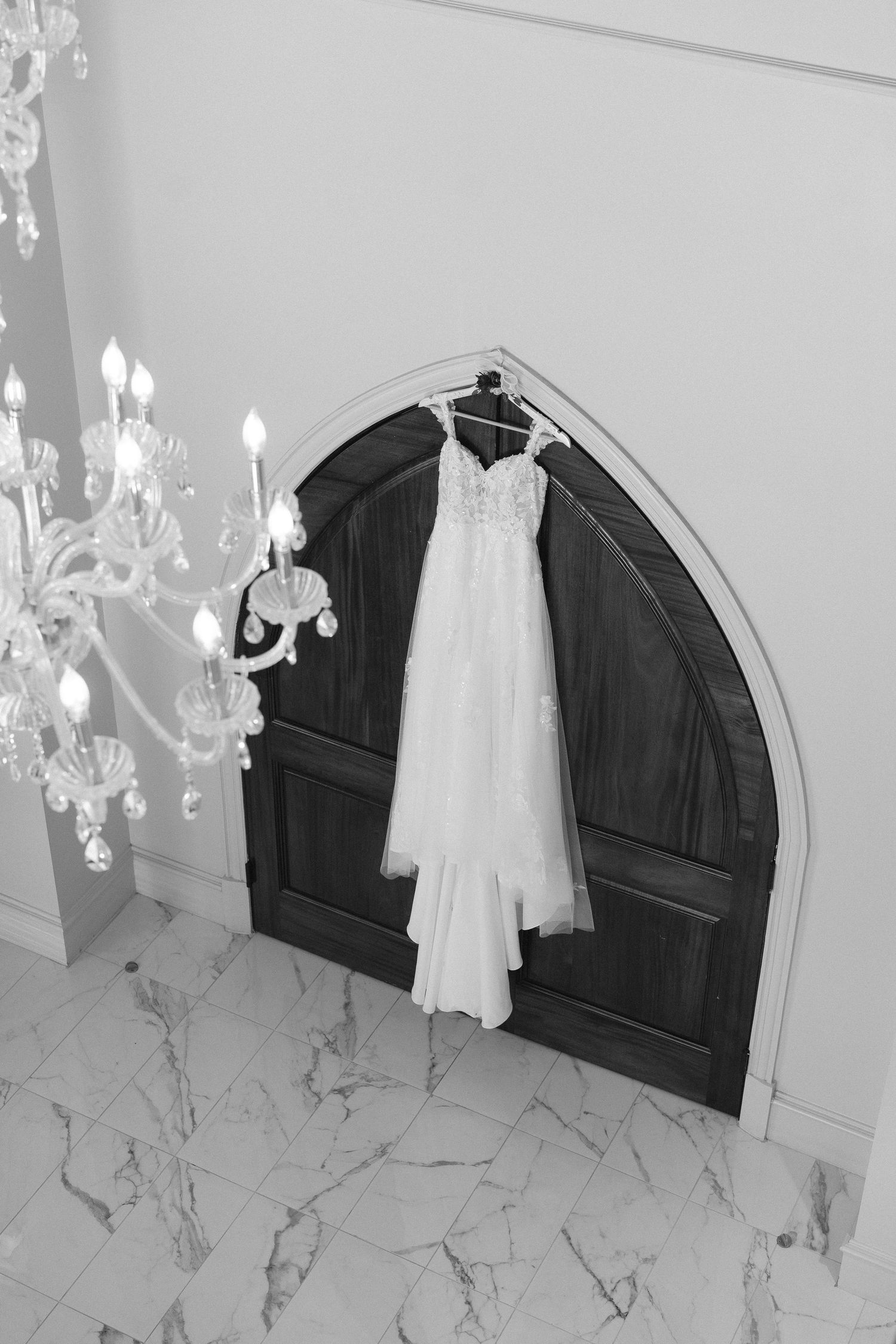Wedding dress displayed in elegant marble bathroom with chandelier lighting.