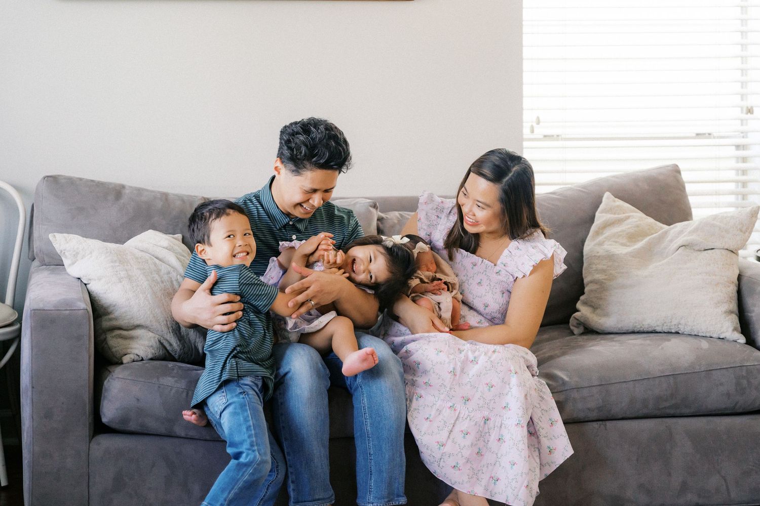 Family relaxes together on gray couch in living room.