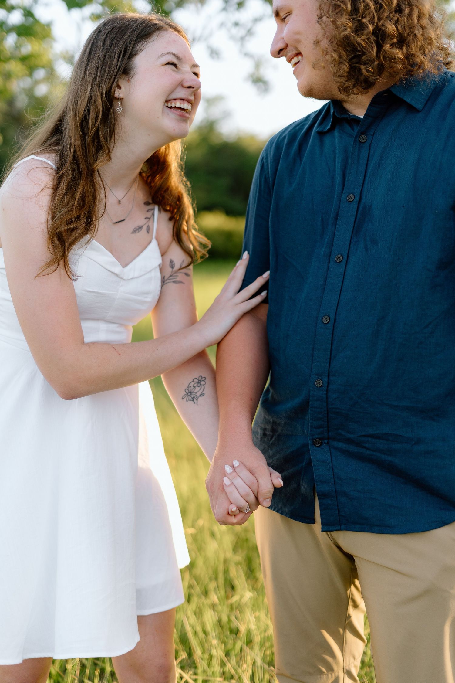 Joyful interaction between couple in white dress and navy shirt against golden field.