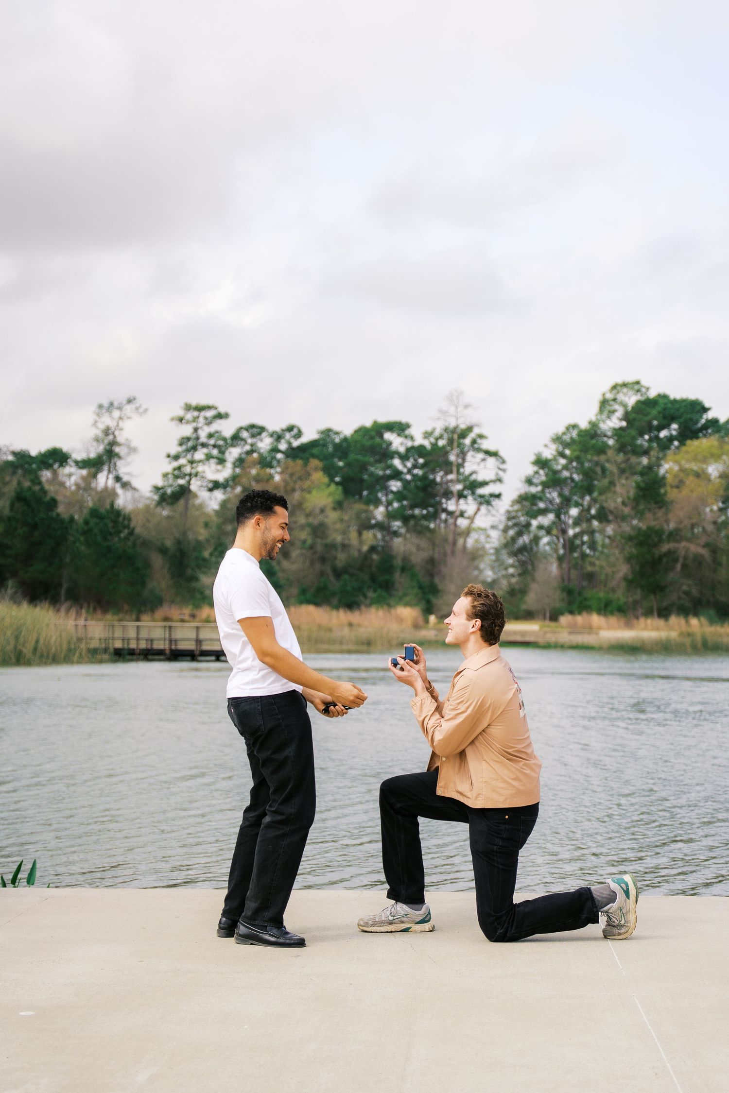 Marriage proposal sequence on a beach boardwalk with water and nature in background.
