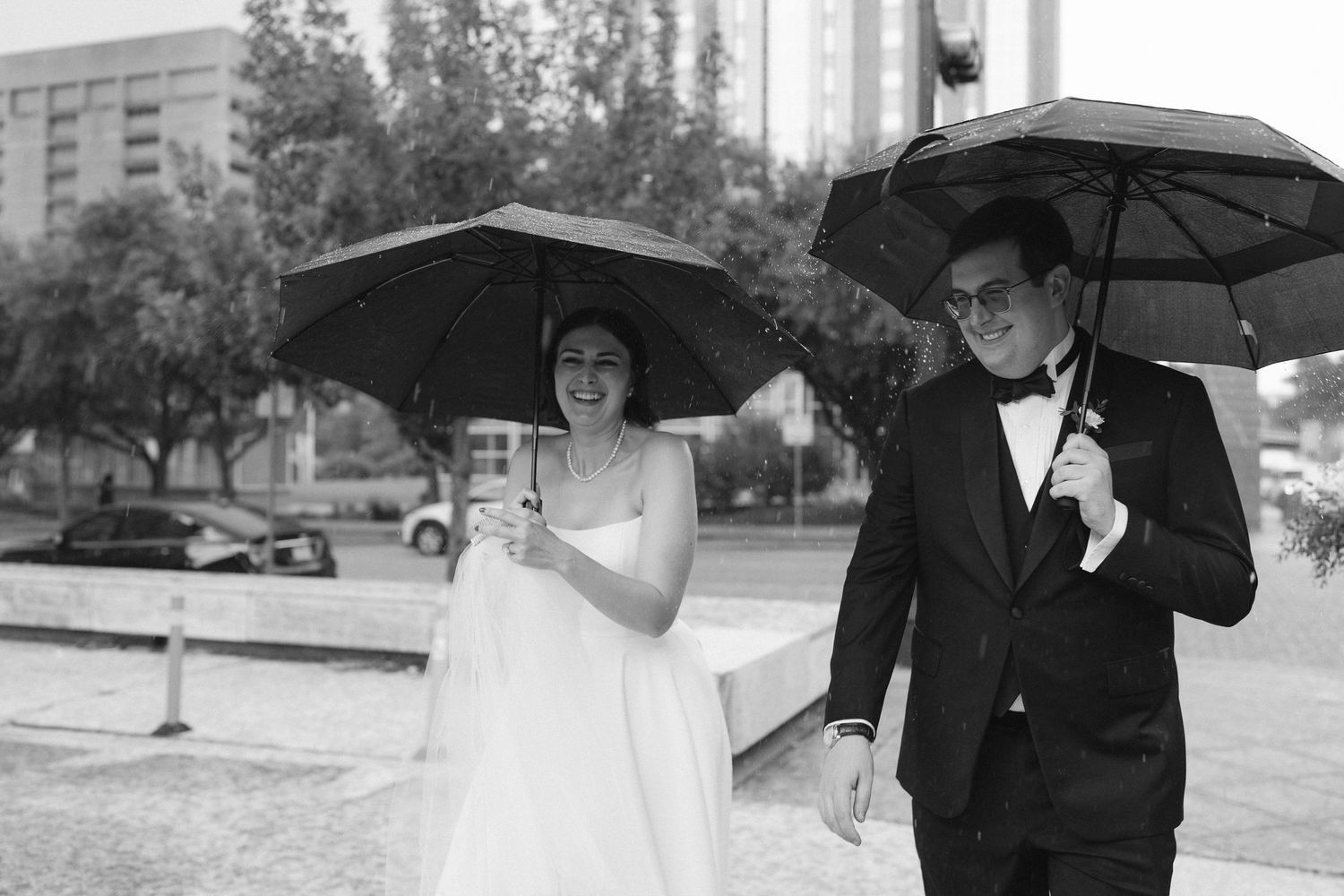 Wedding party holding black umbrellas in a classic black and white photograph.