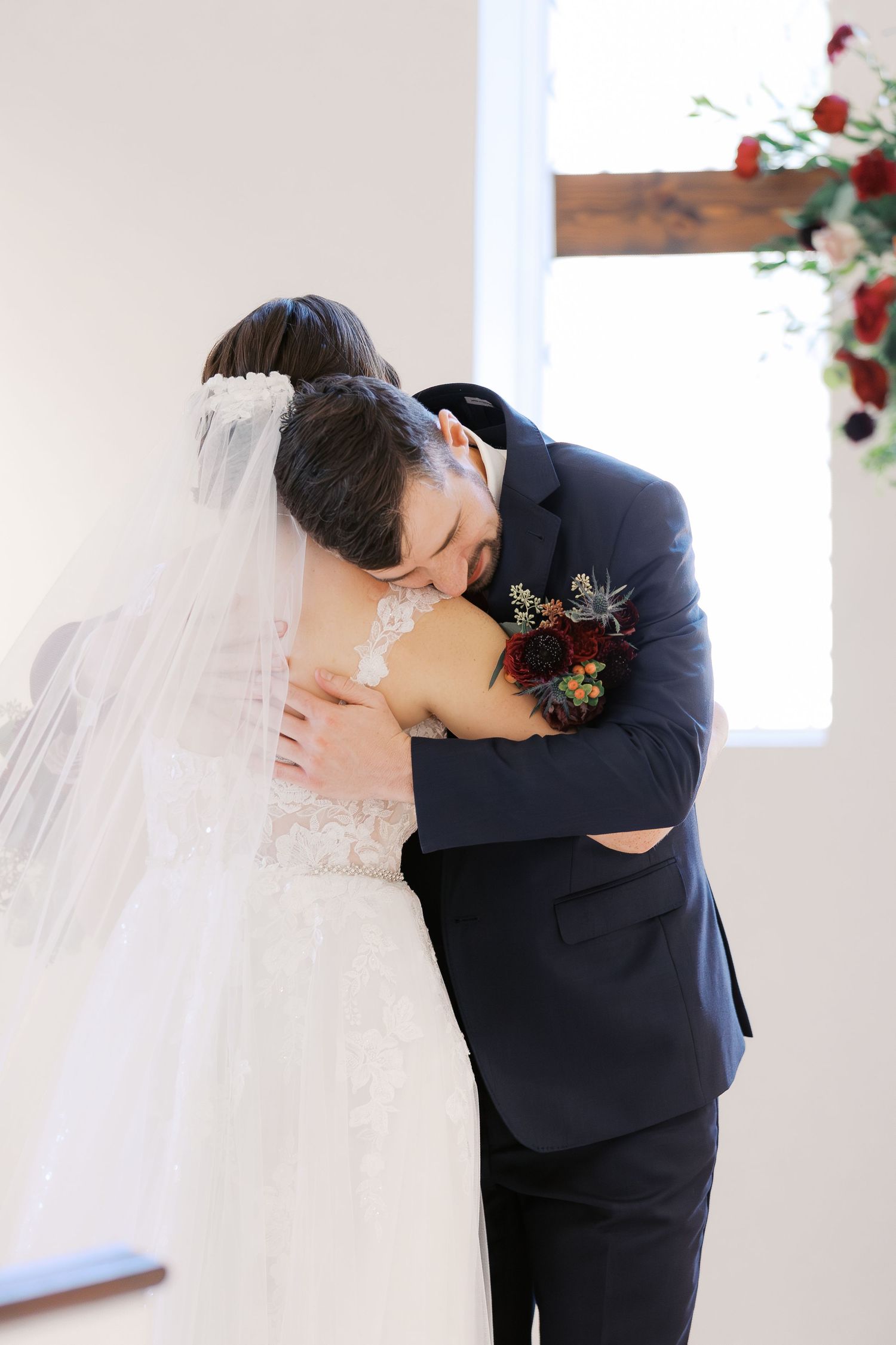 A tender embrace during a wedding first look in a bright church setting.
