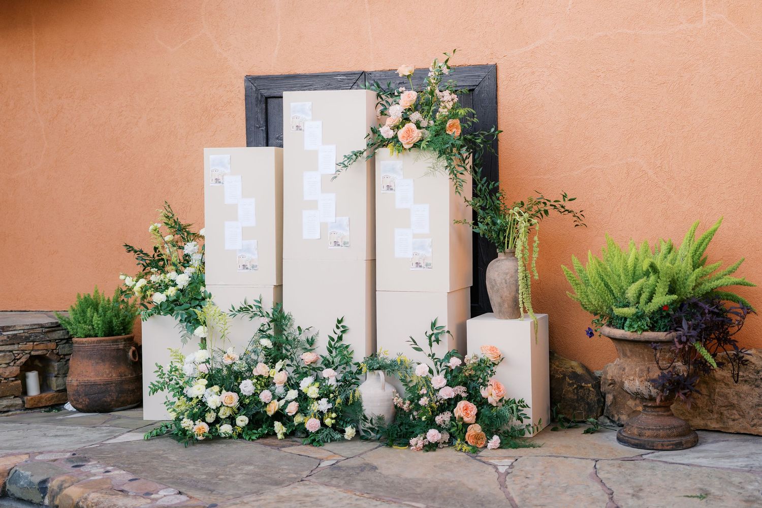 Peach colored stucco wall with white doors and floral decorations along the base.