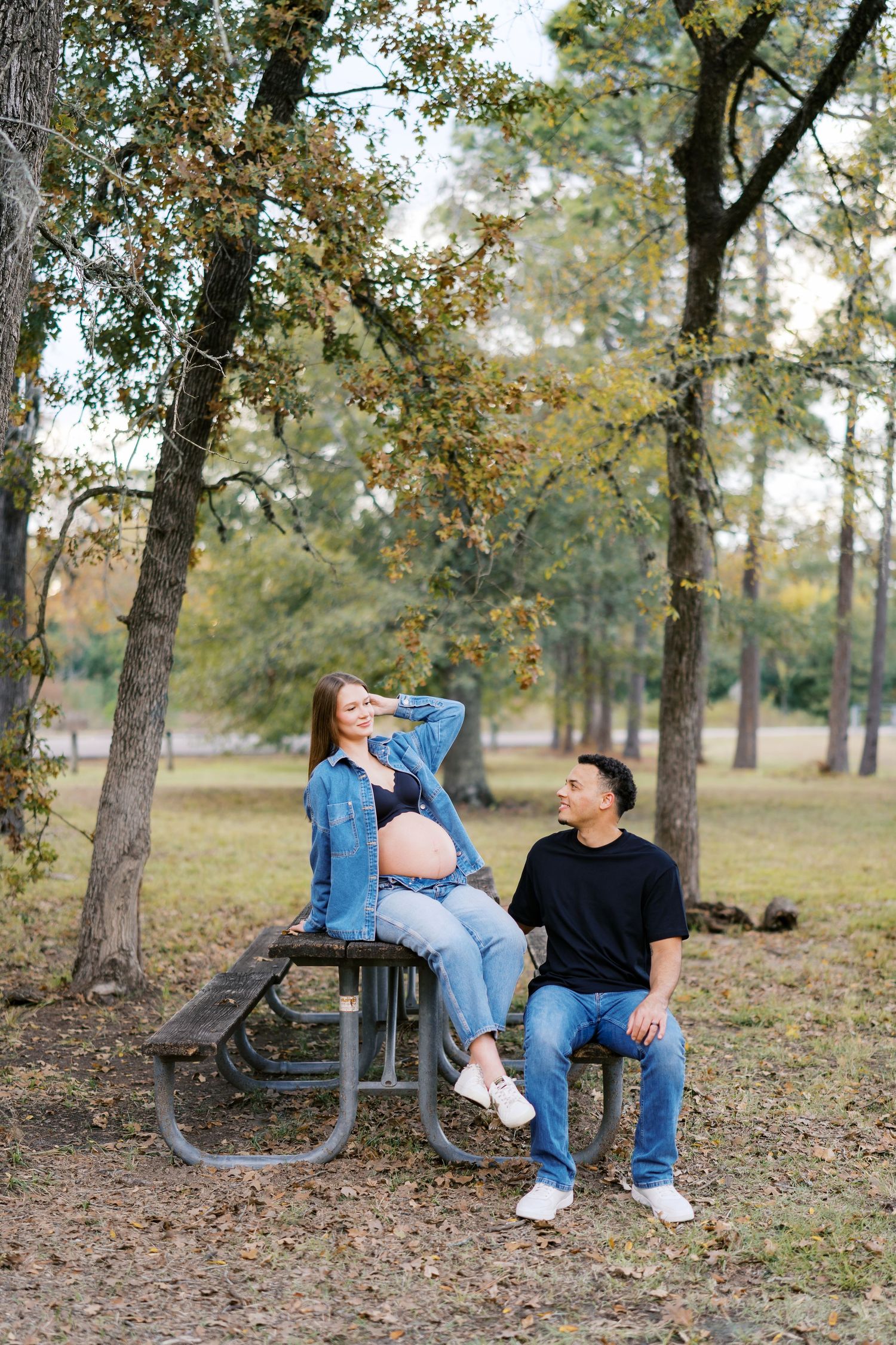 Couple sharing playful moments on a park bench surrounded by autumn trees.