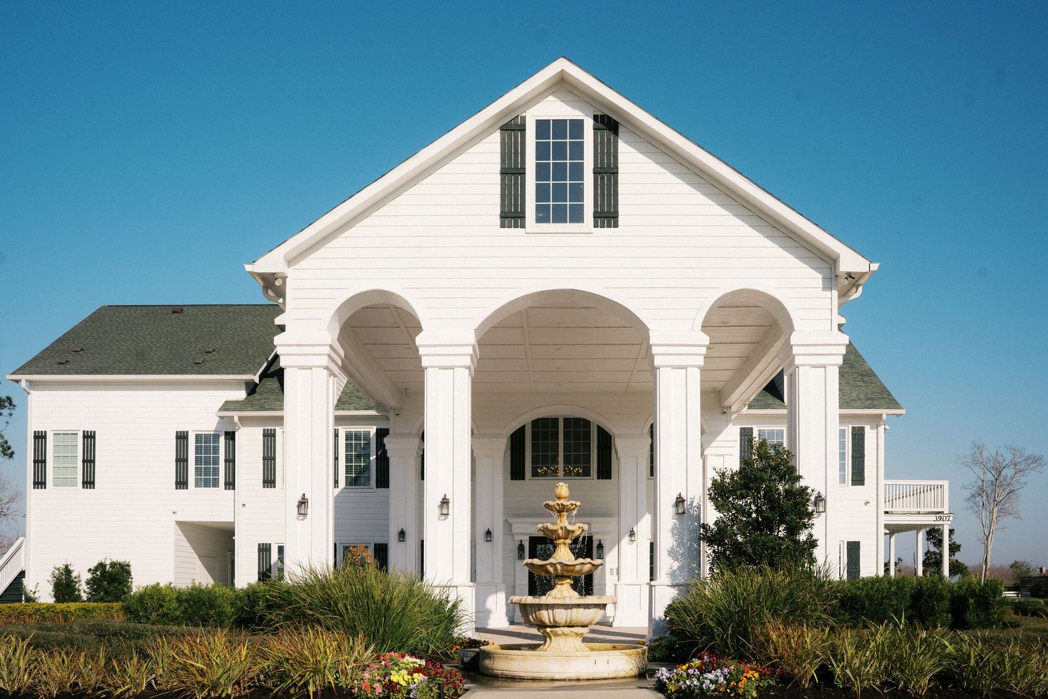 Exterior view of a white wedding venue with classic colonial architecture against blue sky.