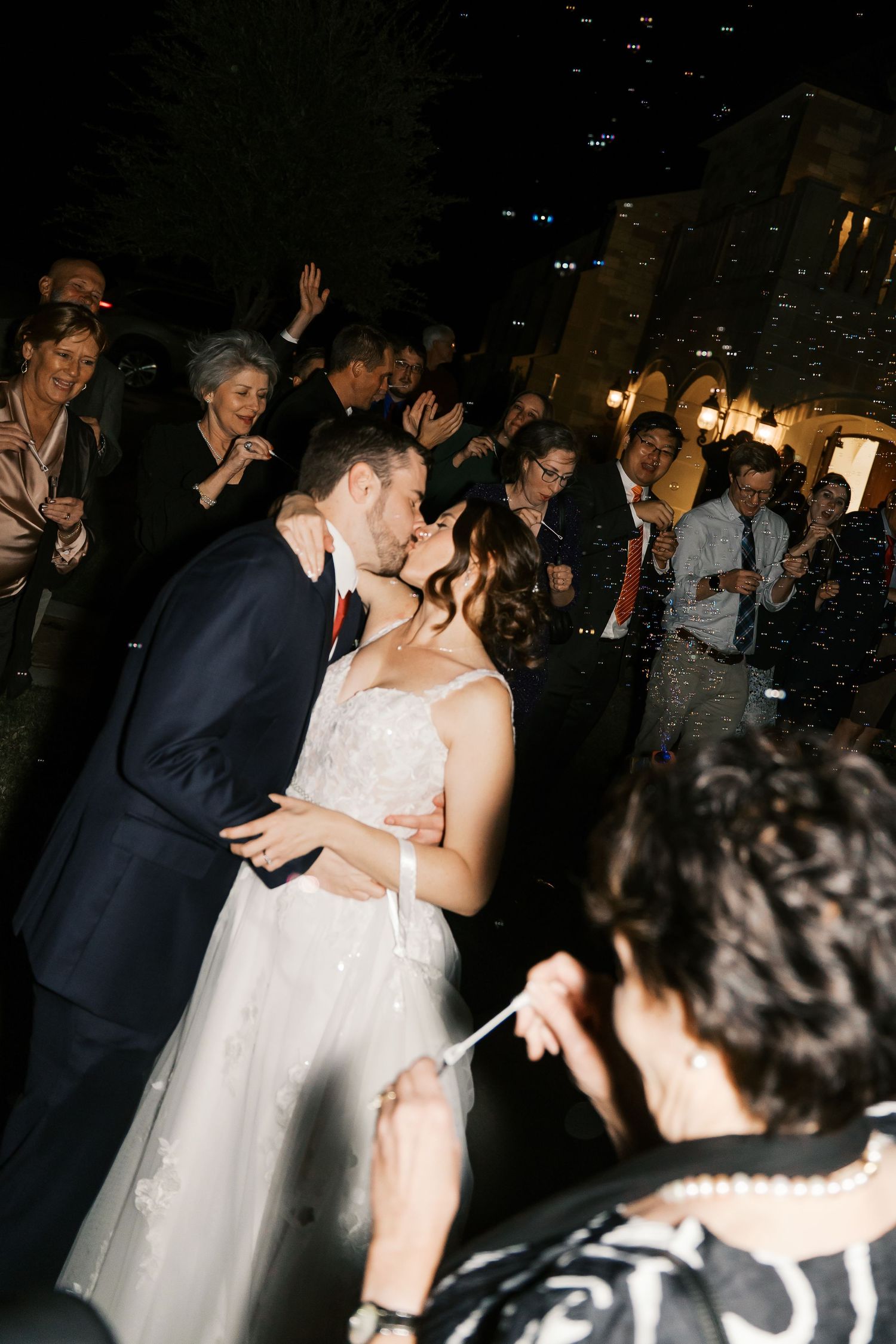 Romantic wedding kiss during the couple's sparkler exit surrounded by celebrating guests.