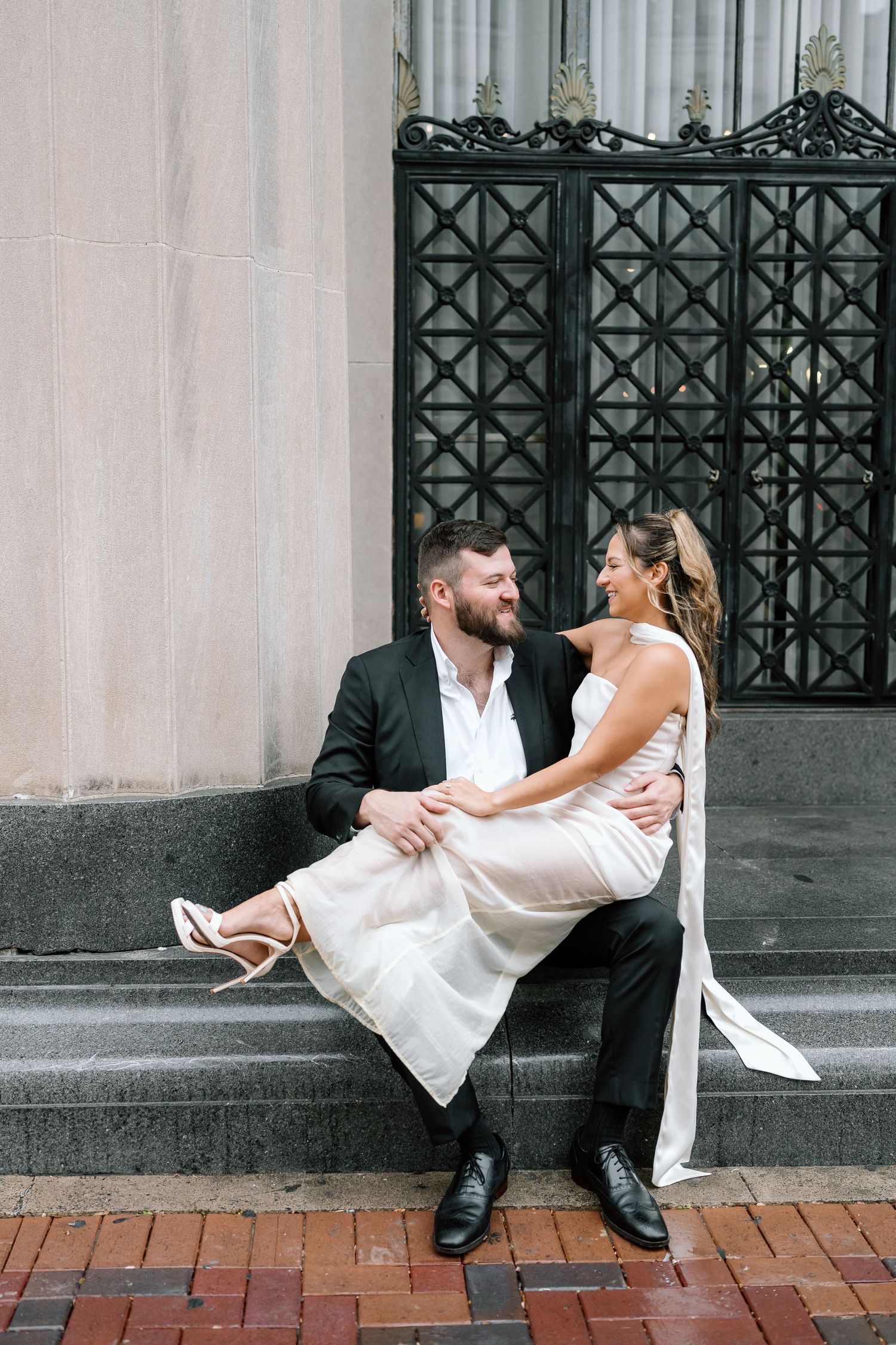 Newlyweds share romantic poses on urban building steps.