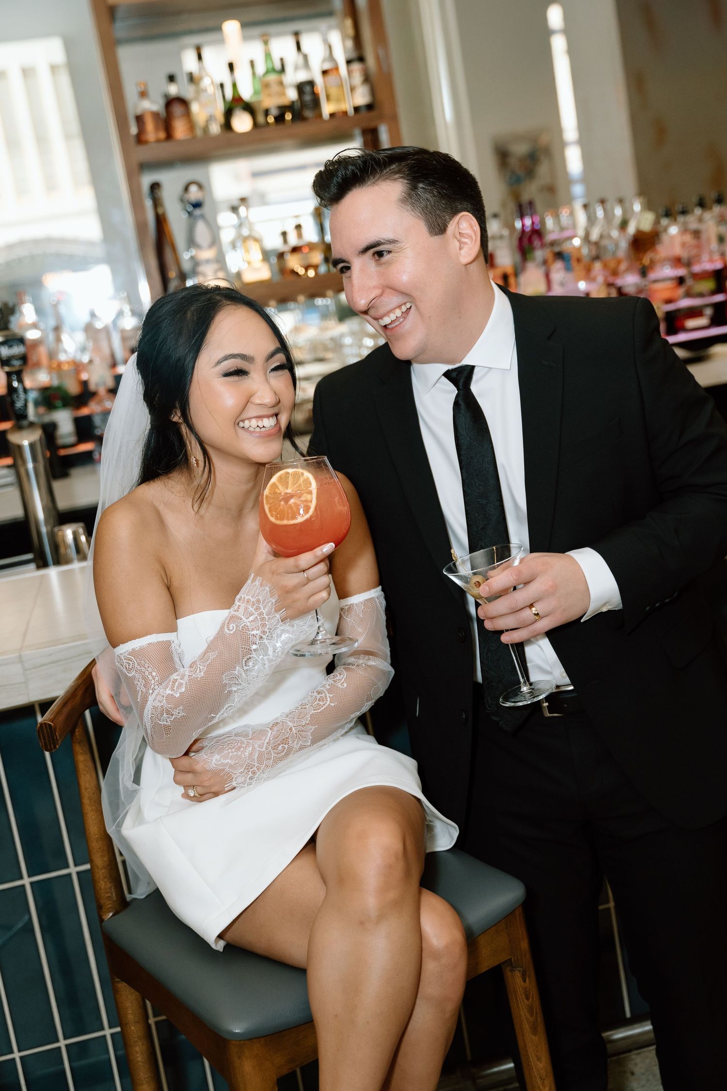 Wedding couple enjoying cocktails at elegant bar setting.