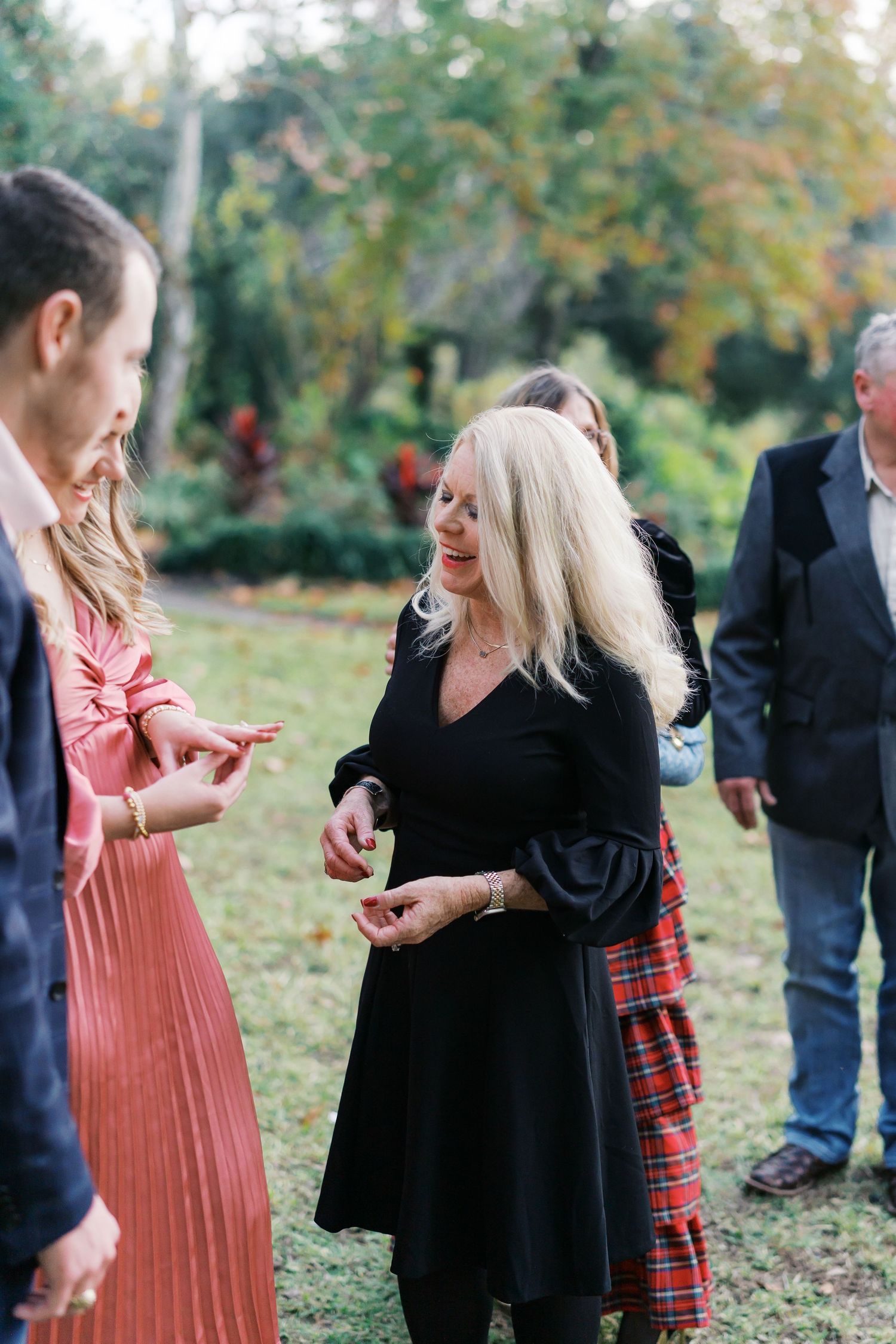 People chatting outdoors with one wearing a red plaid skirt and another in black.