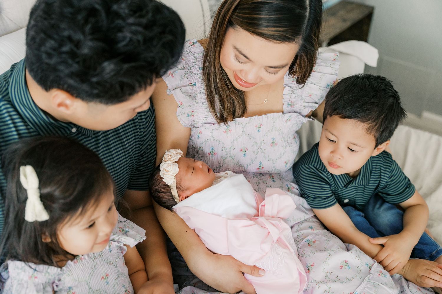 A family bonding with their newborn baby on a comfortable bed.