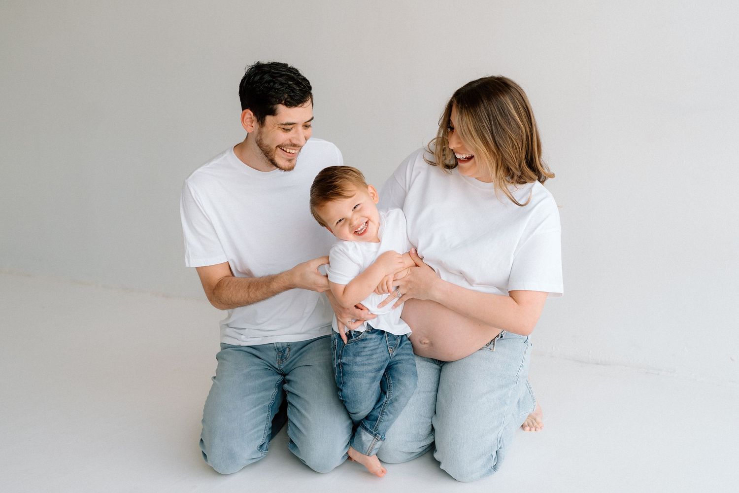 A family in casual attire sharing playful moments on a white background.
