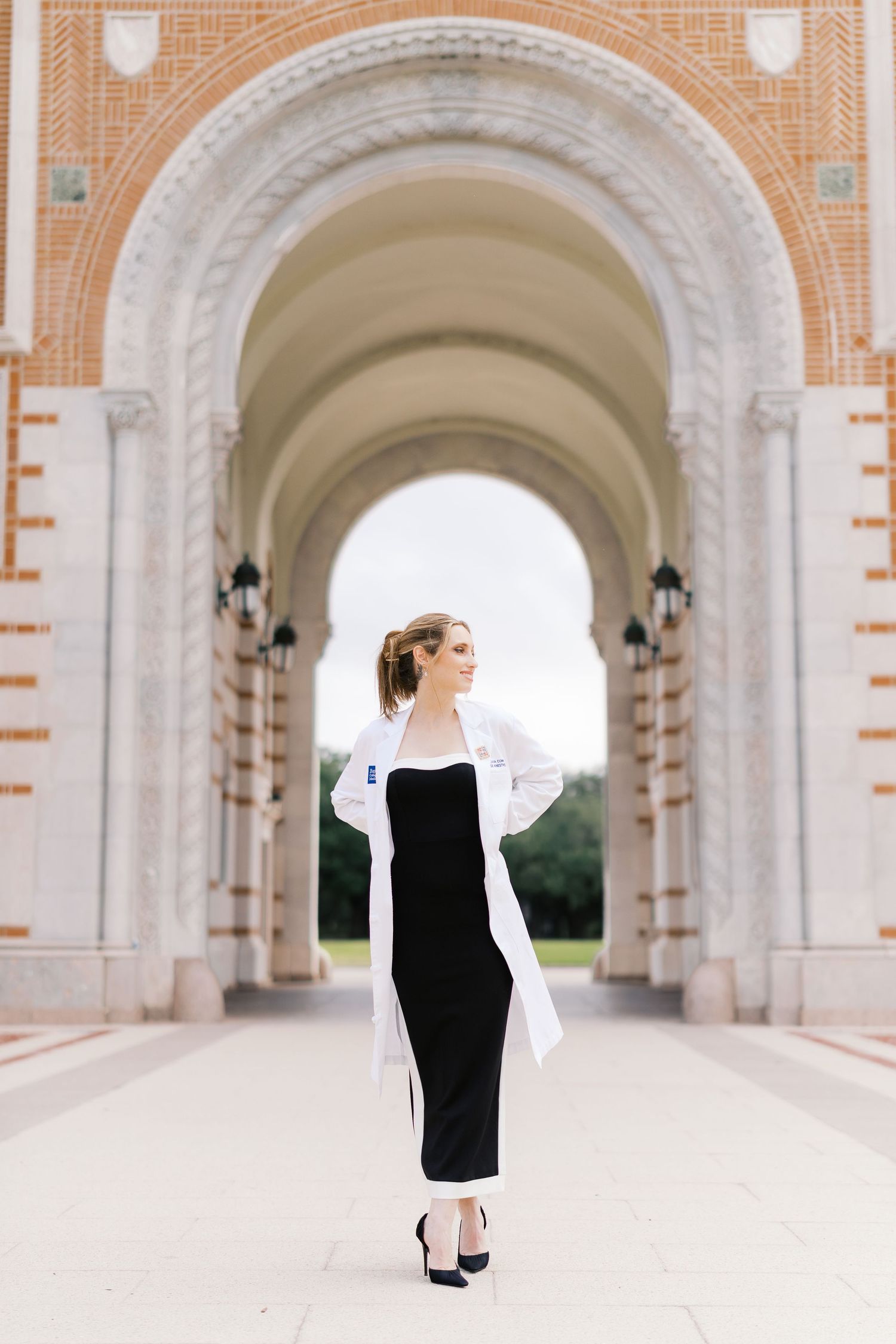 Figure in black and white outfit walking through grand architectural colonnade.