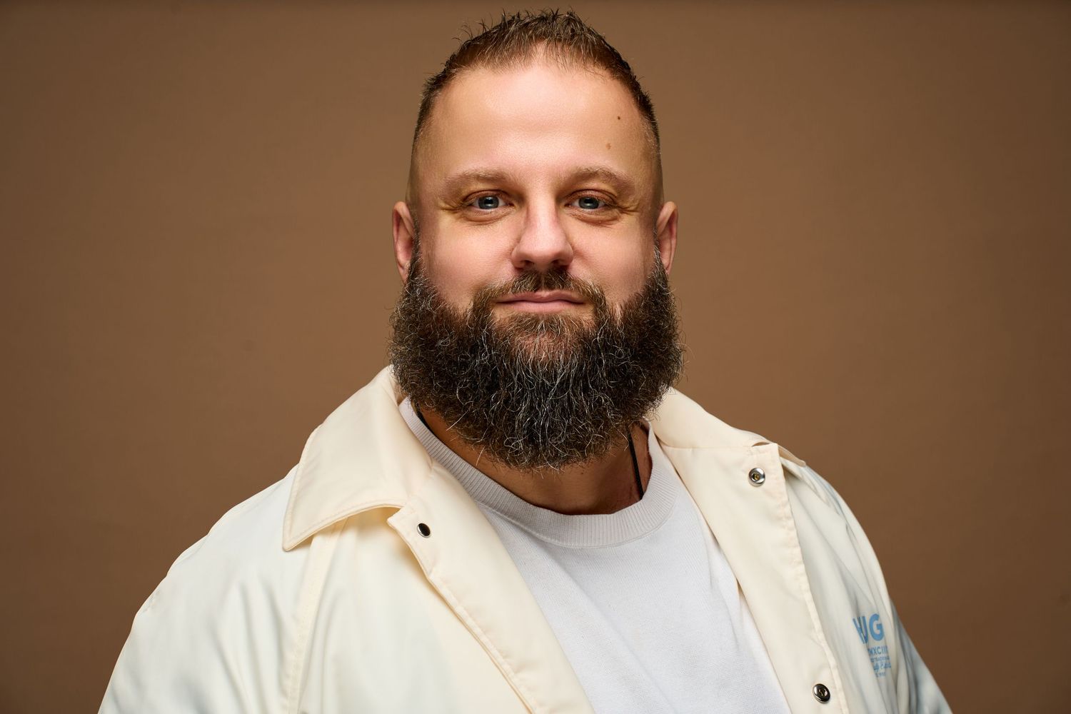 Professional headshot series showing a bearded person in white shirt against brown background making various expressions.