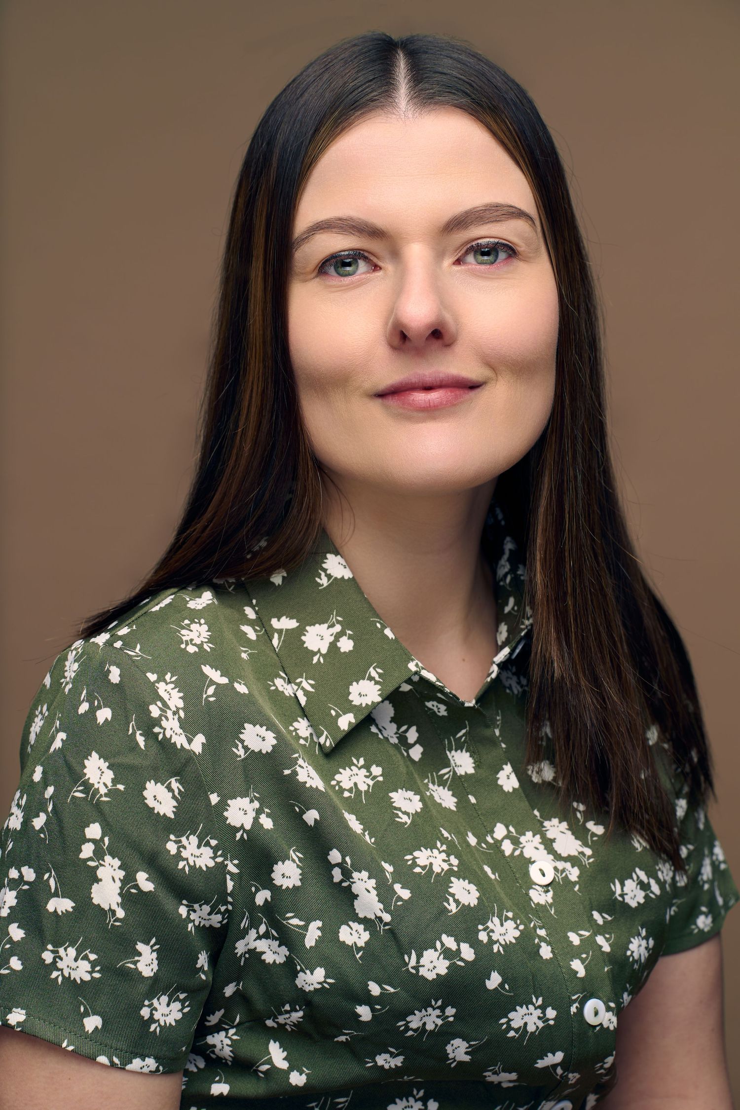 Professional headshot of a young woman in a green floral dress.