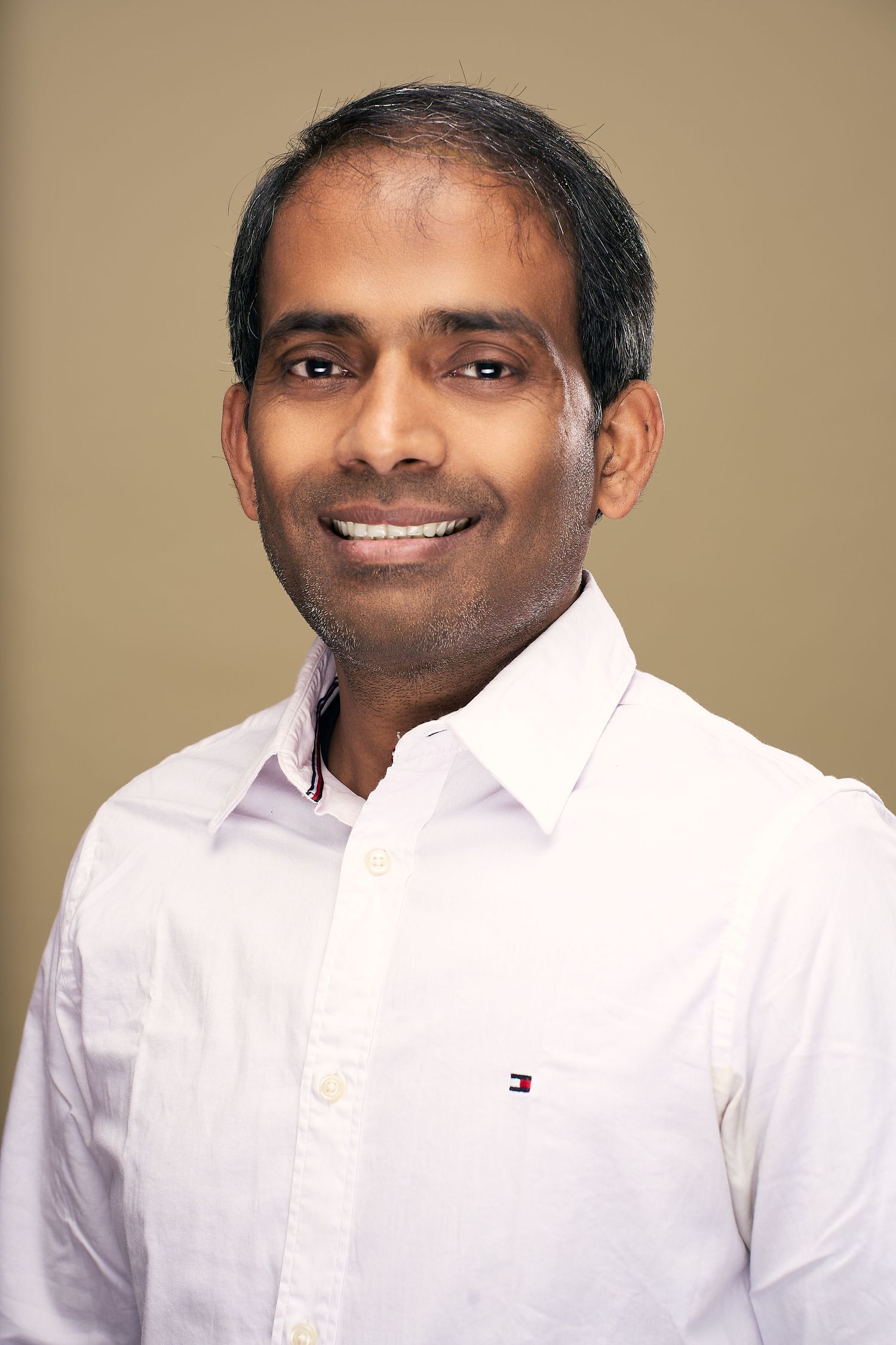 Professional headshot of a person in a white button-down shirt against a neutral background showing different expressions.