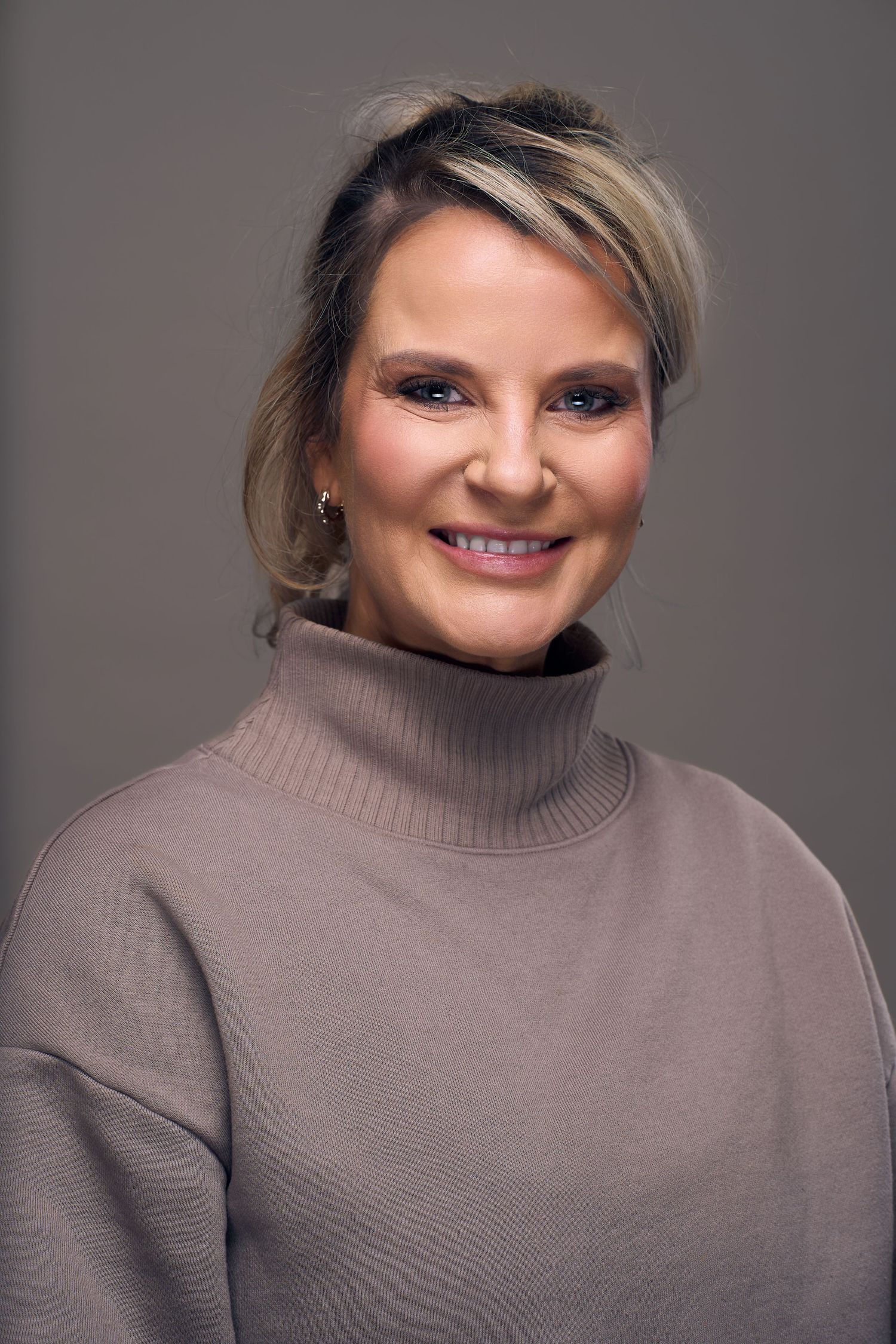 A sequence of five portraits showing someone in a beige turtleneck sweater against a gray background with varying expressions.