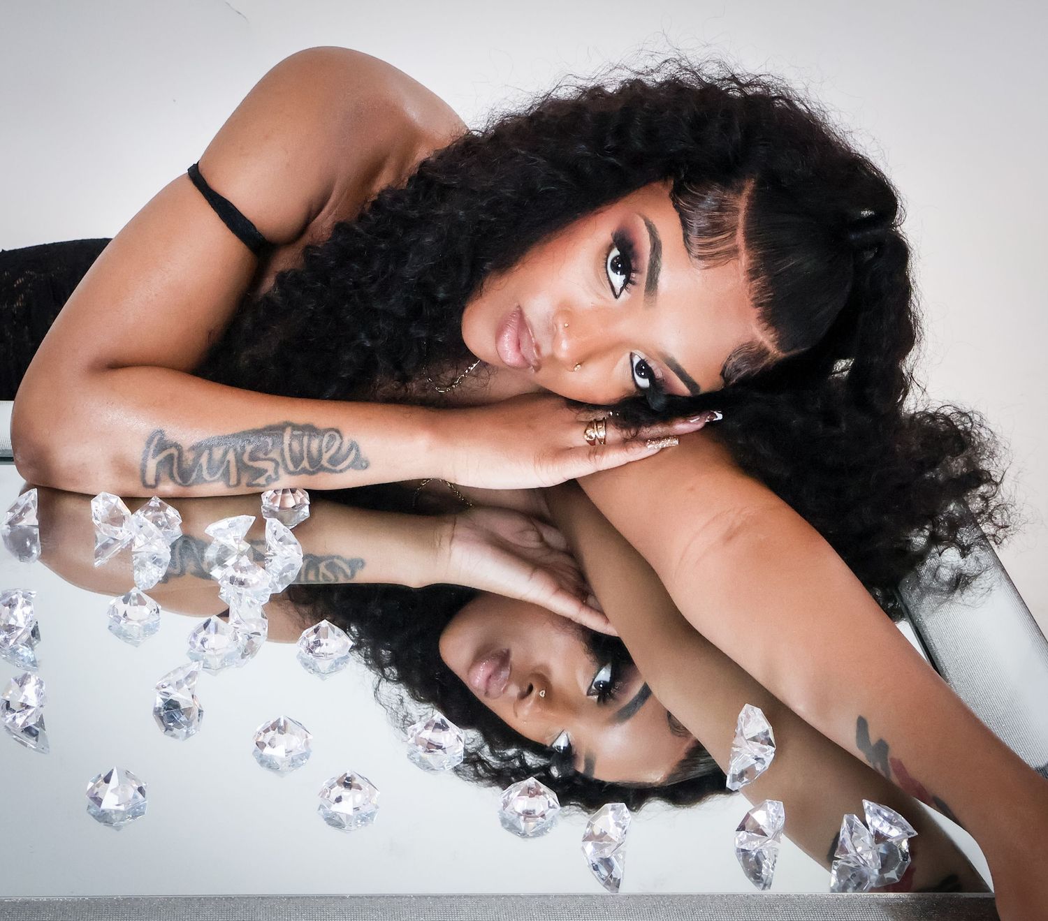 Woman with curly hair posing on mirror with diamonds.