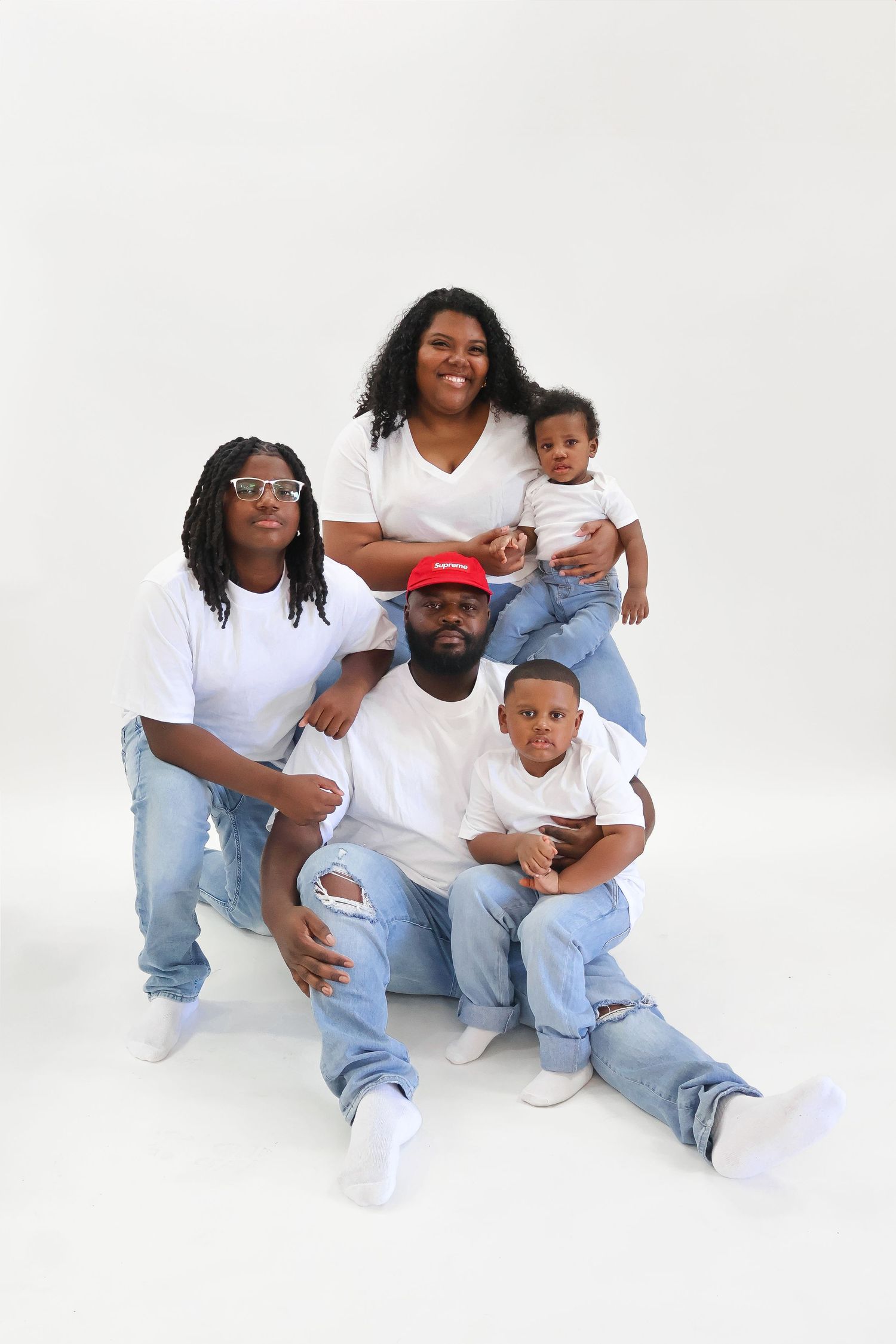 Family of five in matching white shirts and jeans posing together.