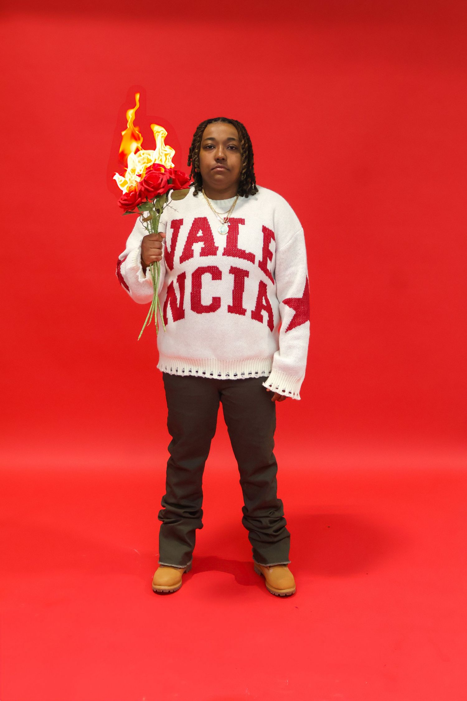 Person in Valencia sweater holding flaming red roses bouquet against bold red background.