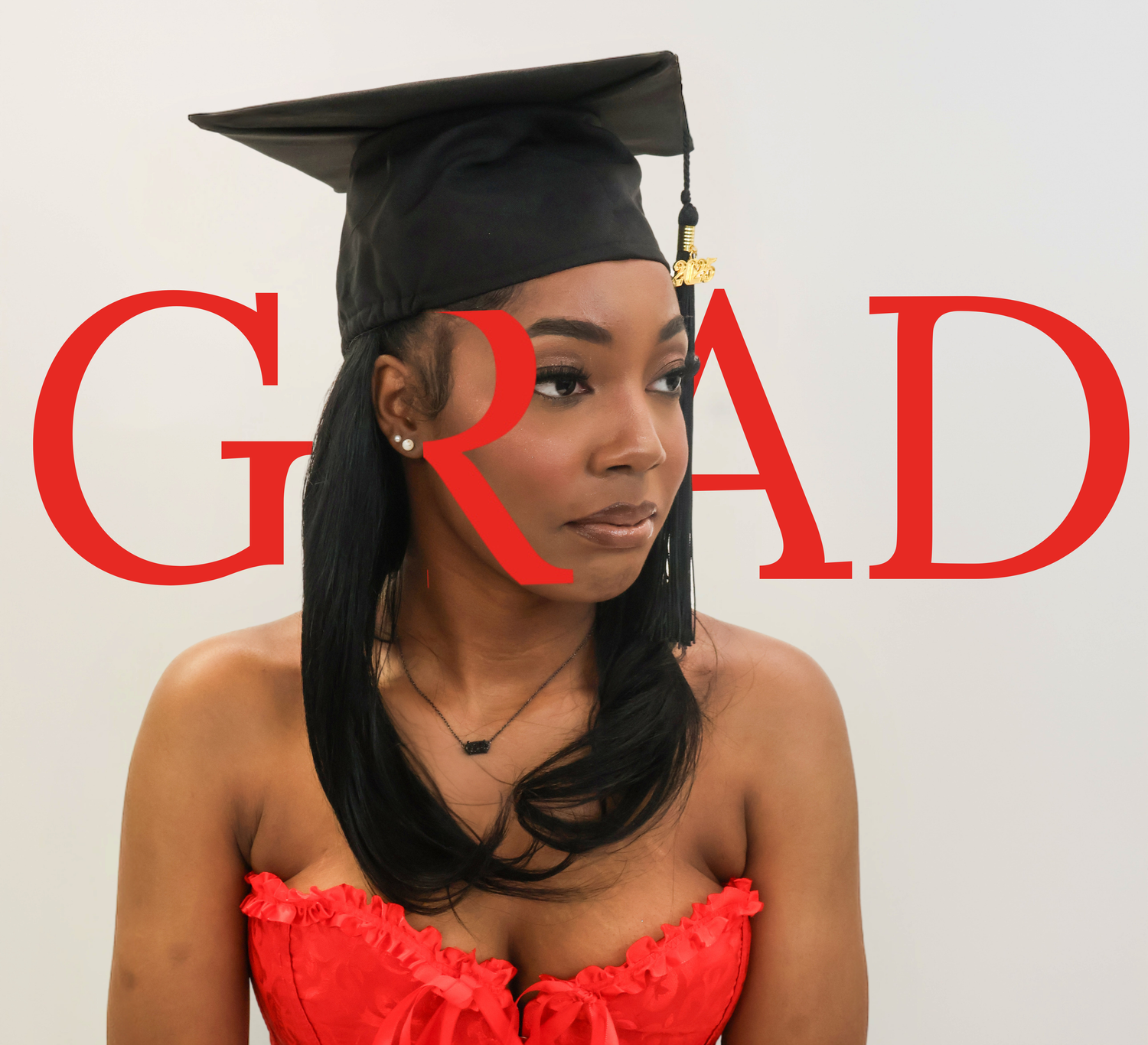 Close-up portrait of graduate in black cap and red dress with bold red GRAD text background.