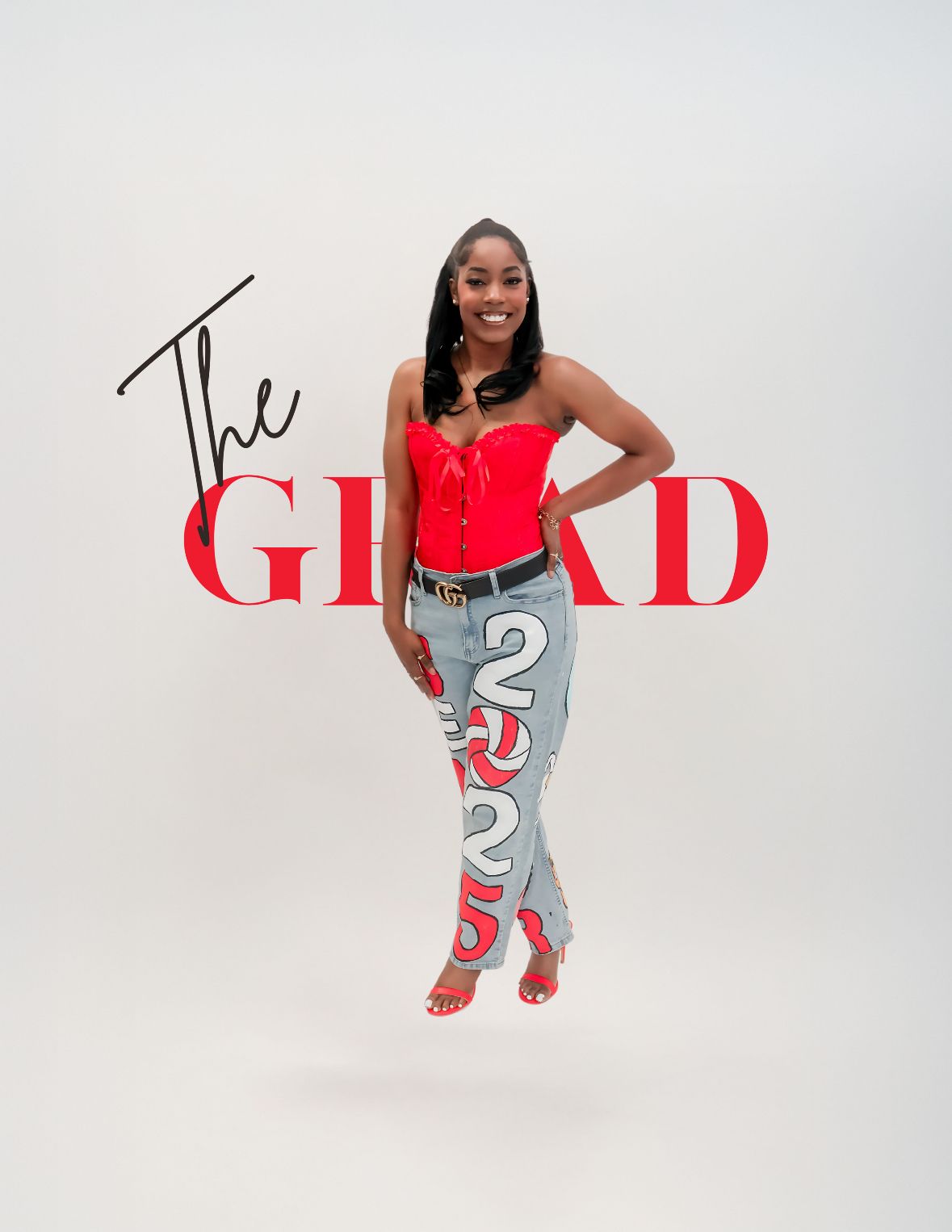 Confident graduate poses in red corset top and custom 2025 painted jeans with The Grad text overlay.
