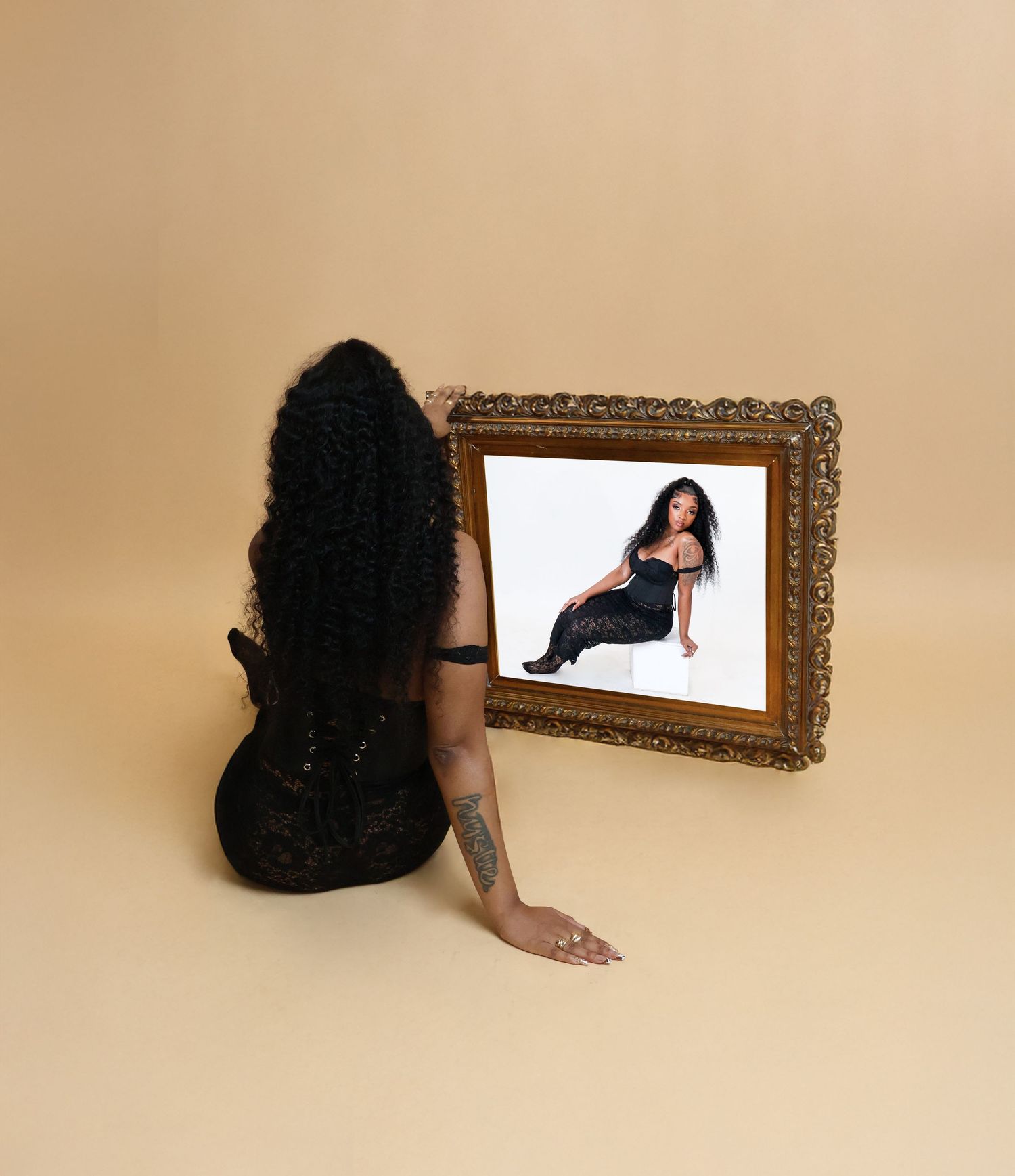 Woman with curly hair viewing her portrait in ornate gold frame.