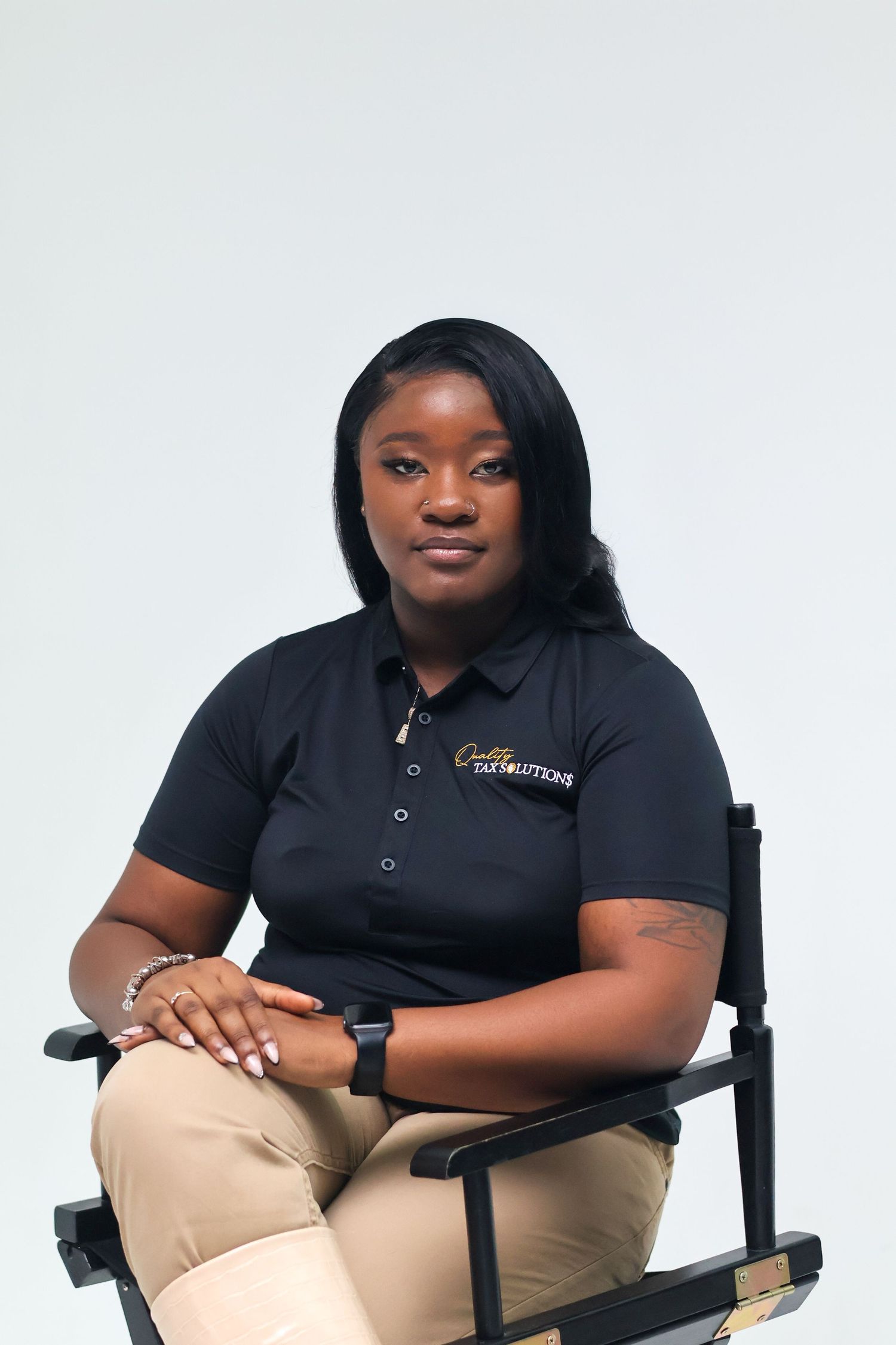 Professional woman in black Caddie Tax Solutions polo shirt seated in director's chair.