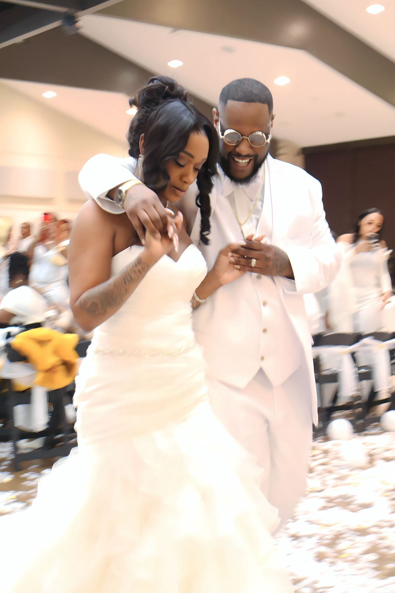 Bride in ruffled mermaid gown and groom in white suit share joyful first dance together.