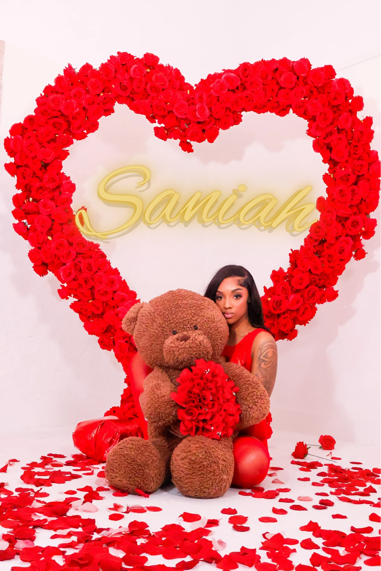 Woman posing with teddy bear inside large red rose heart frame with name Samiah.