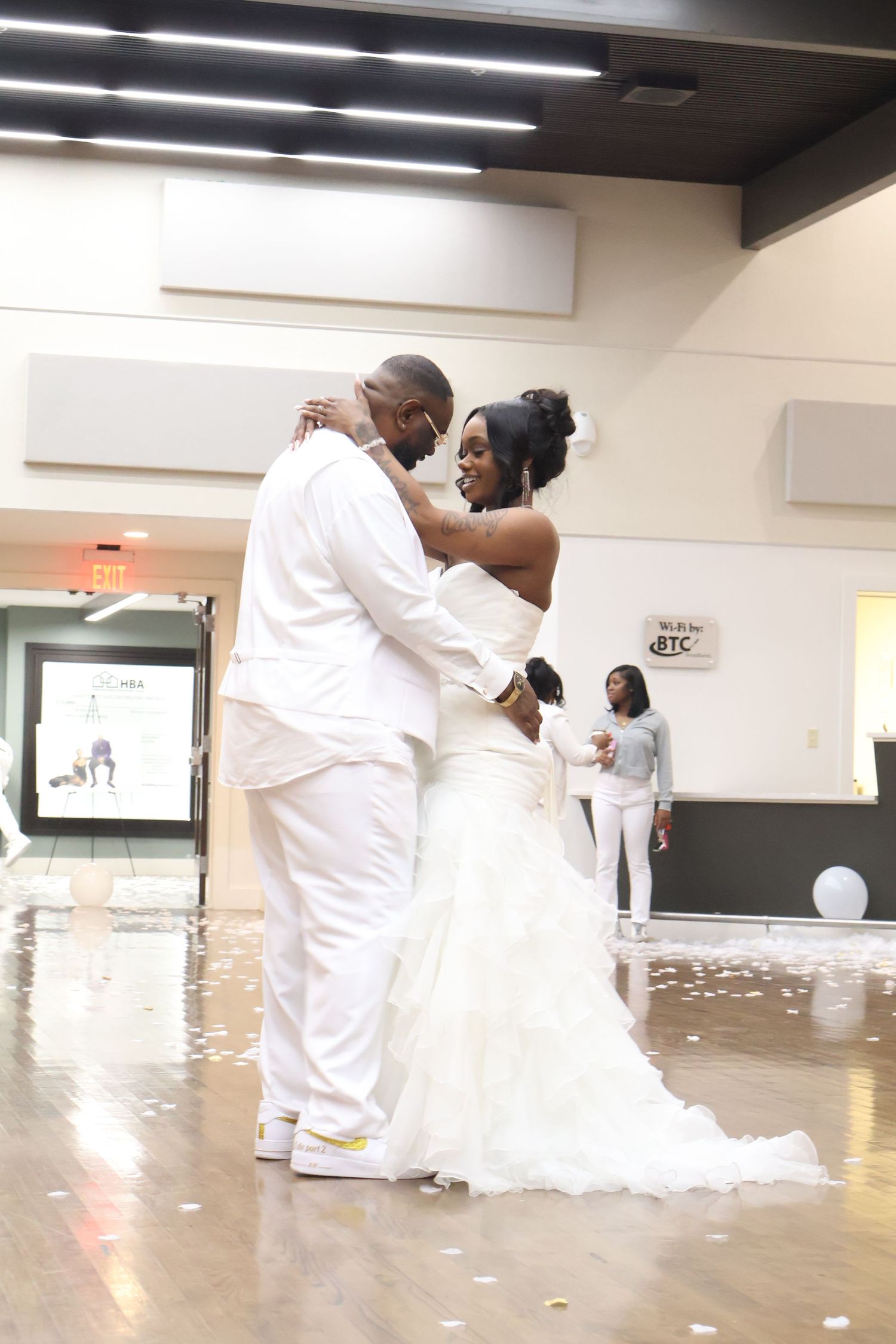 Bride and groom share their first dance in white wedding attire on a decorated dance floor at their wedding reception.