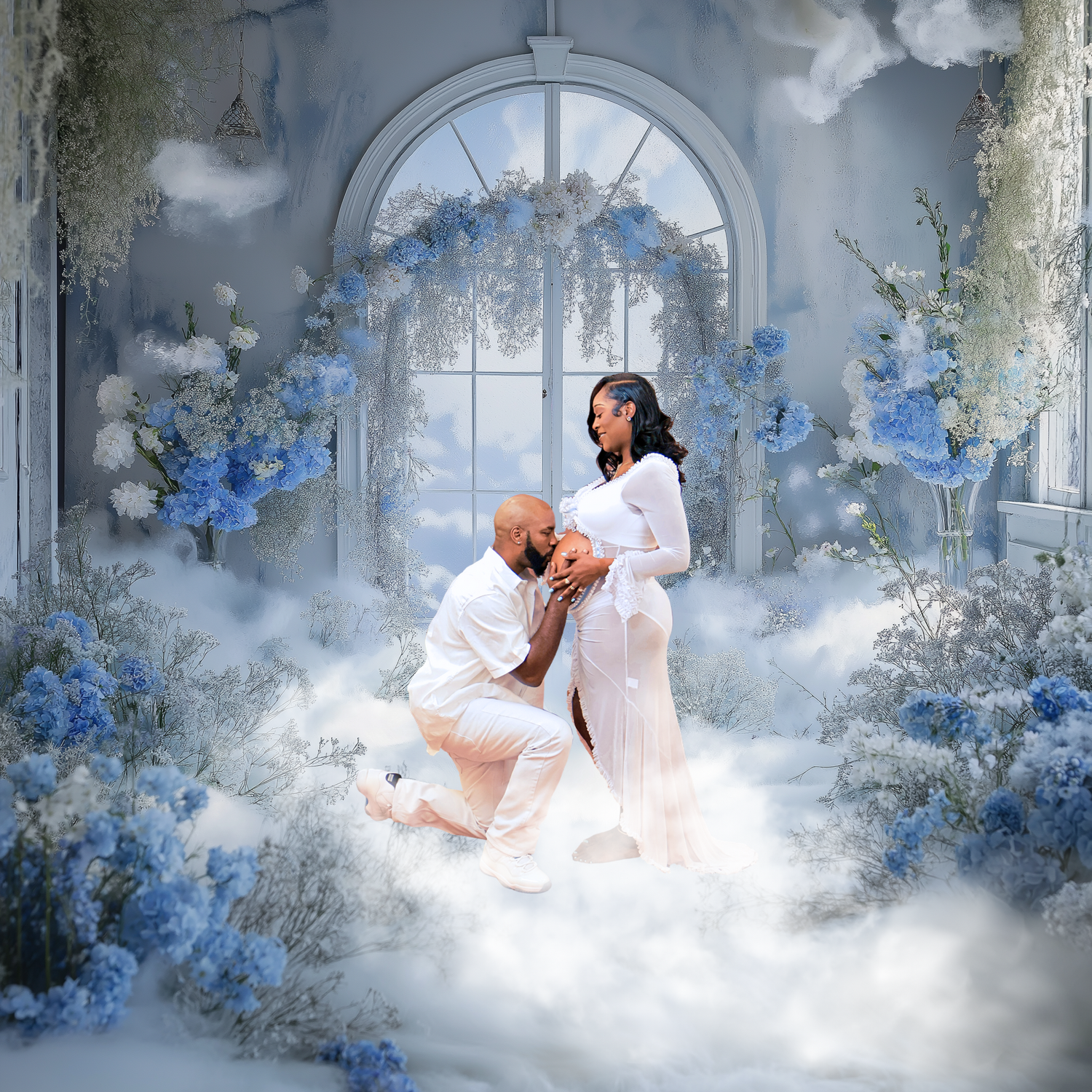 Romantic maternity photo shoot with couple in white surrounded by blue flowers and dreamy clouds in elegant studio.