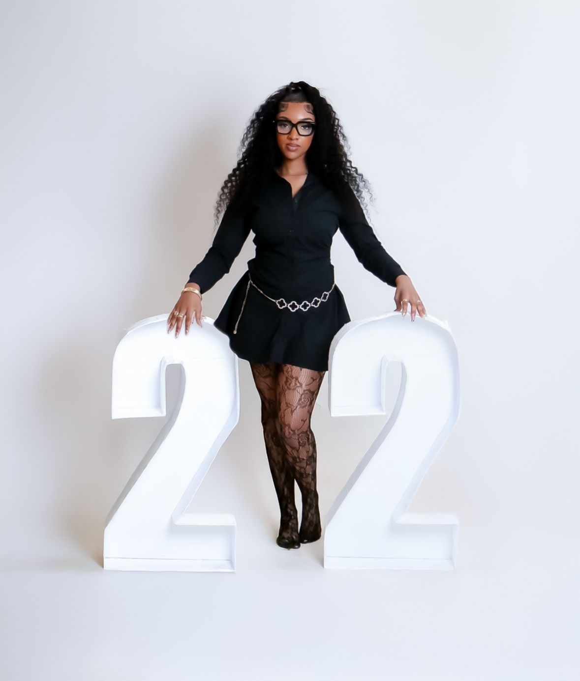 Woman in black outfit posing between large number 22 props.
