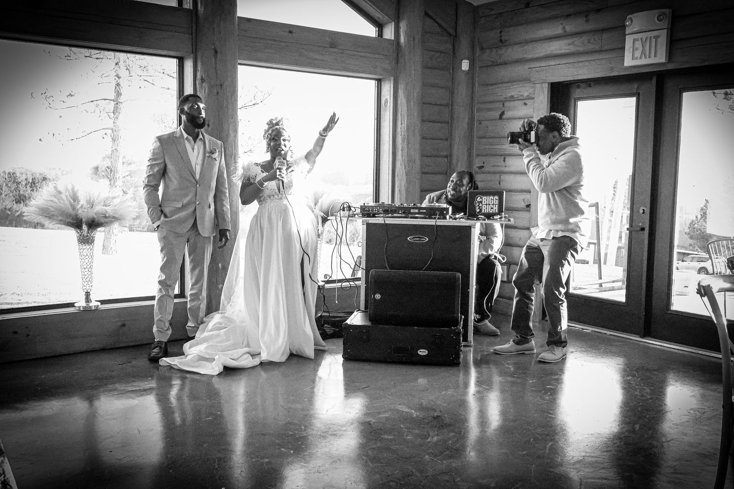 Bride and groom share a moment while a photographer captures the scene in a rustic venue.