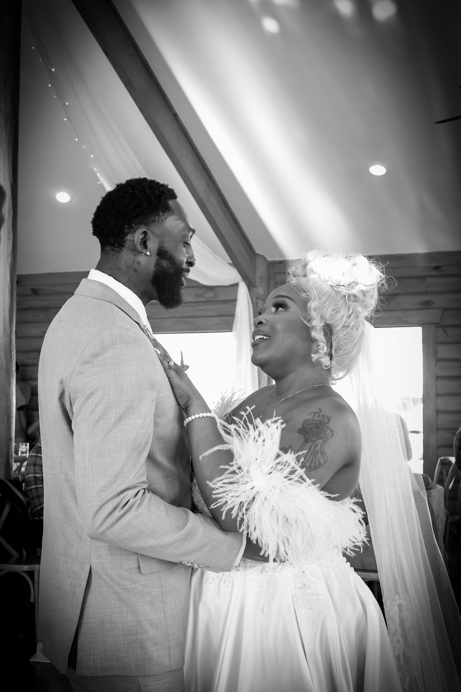 Bride and groom sharing intimate moment in black and white rustic venue portrait.