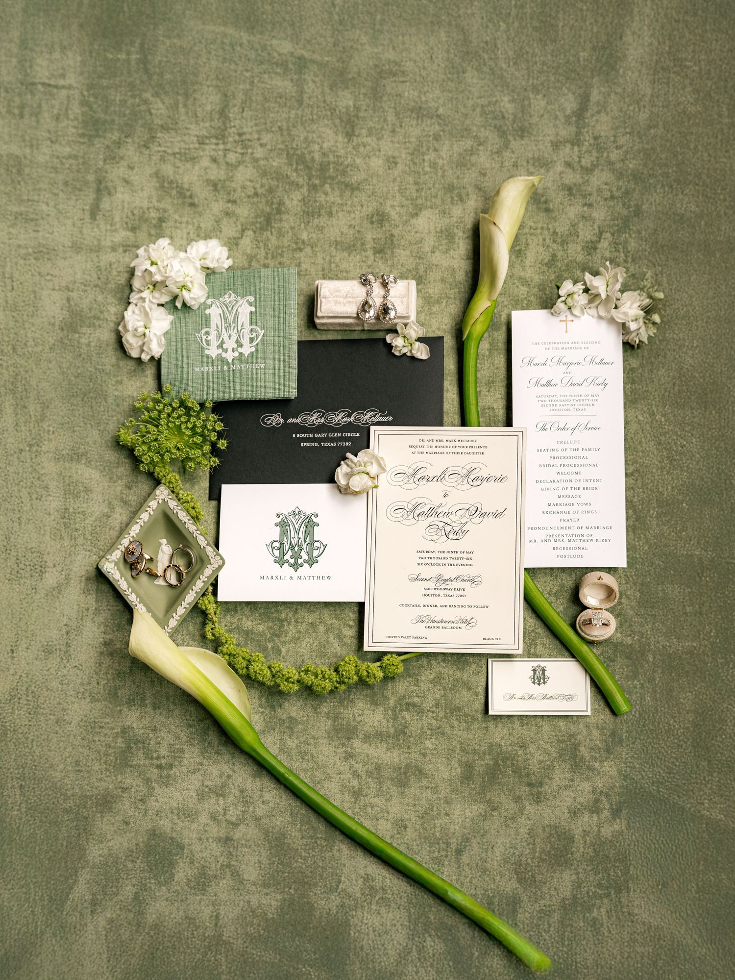 Elegant green and white wedding invitation suite with calla lilies and floral accents on a velvet background.
