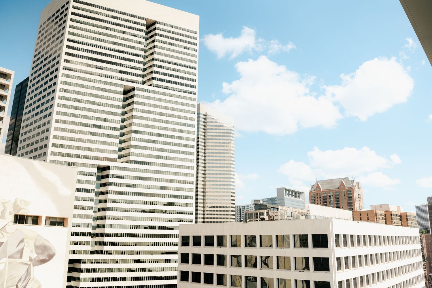 Modern office building with striped facade photographed against bright blue sky with clouds.