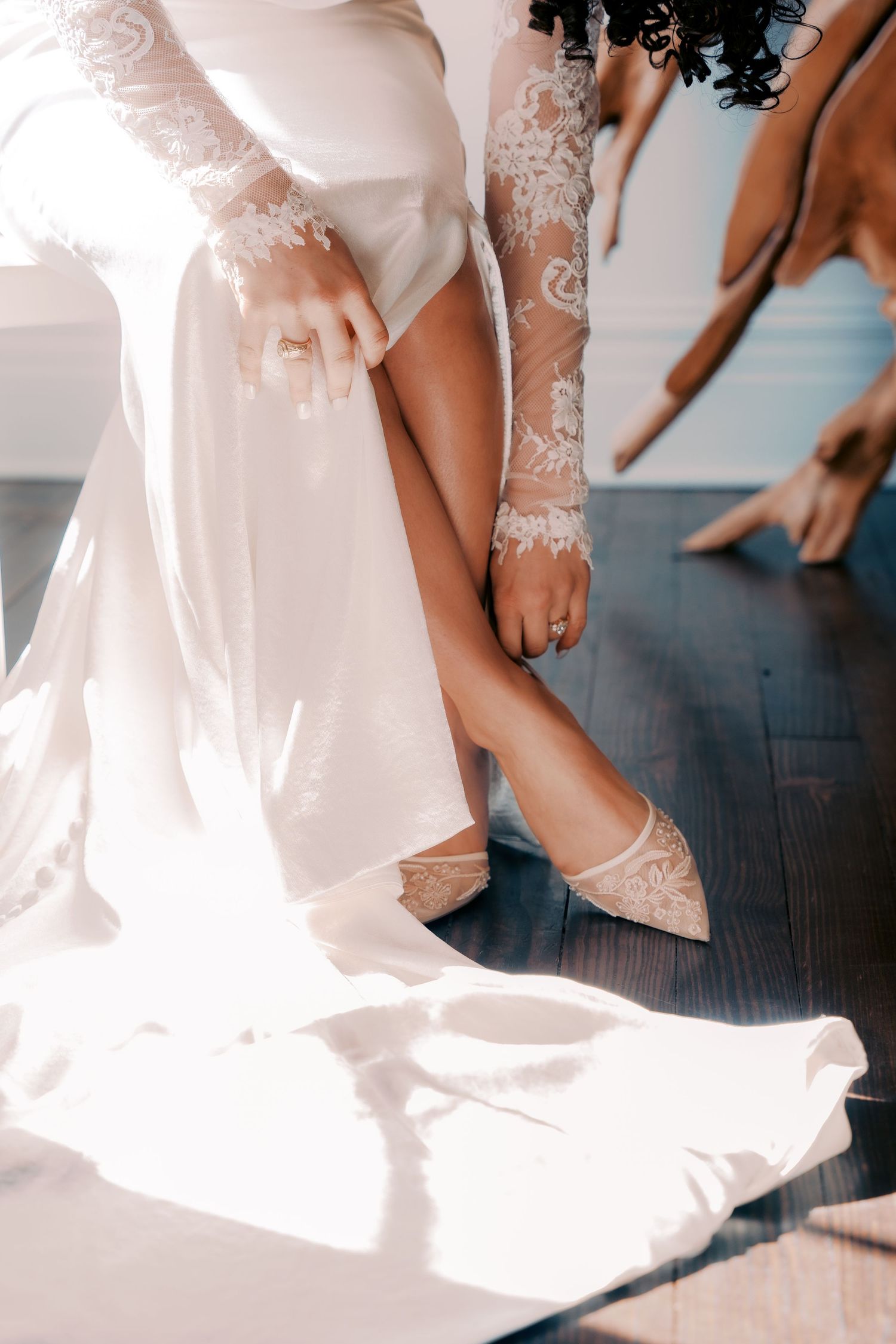 Detail shot of bride's embroidered sleeve and pointed toe shoe with wedding dress flowing.