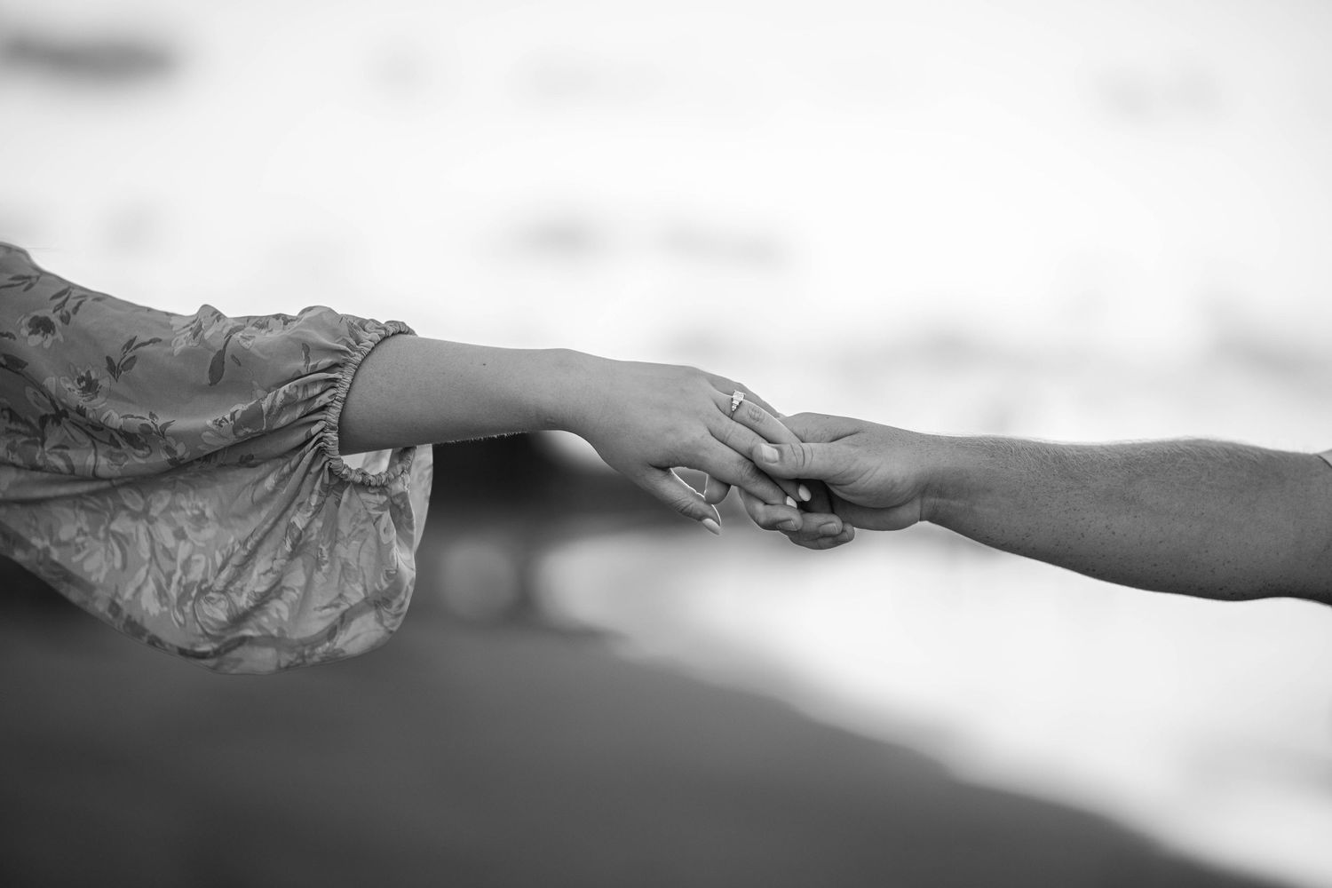 Black and white image of two hands reaching toward each other.