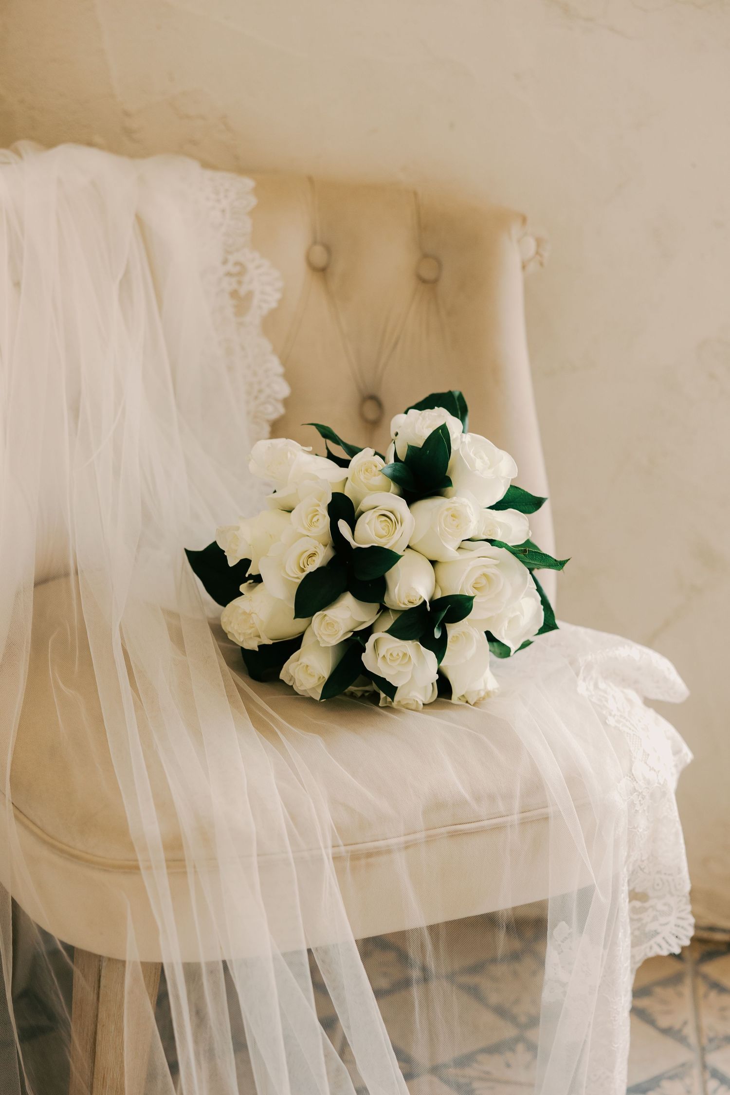 White roses and sheer veil arranged artistically on neutral background.