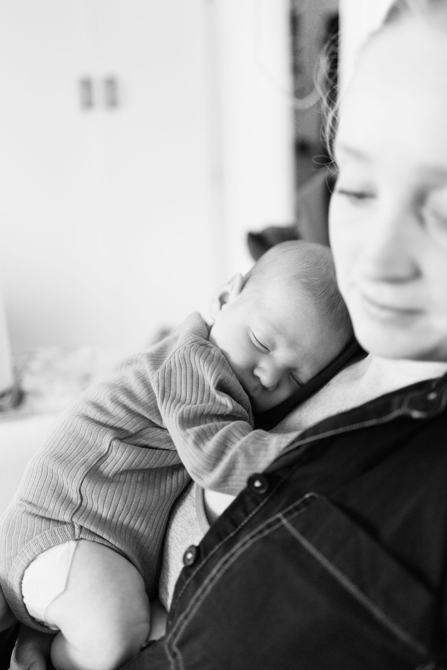 Black and white photo of a newborn baby sleeping peacefully on a young woman's chest.