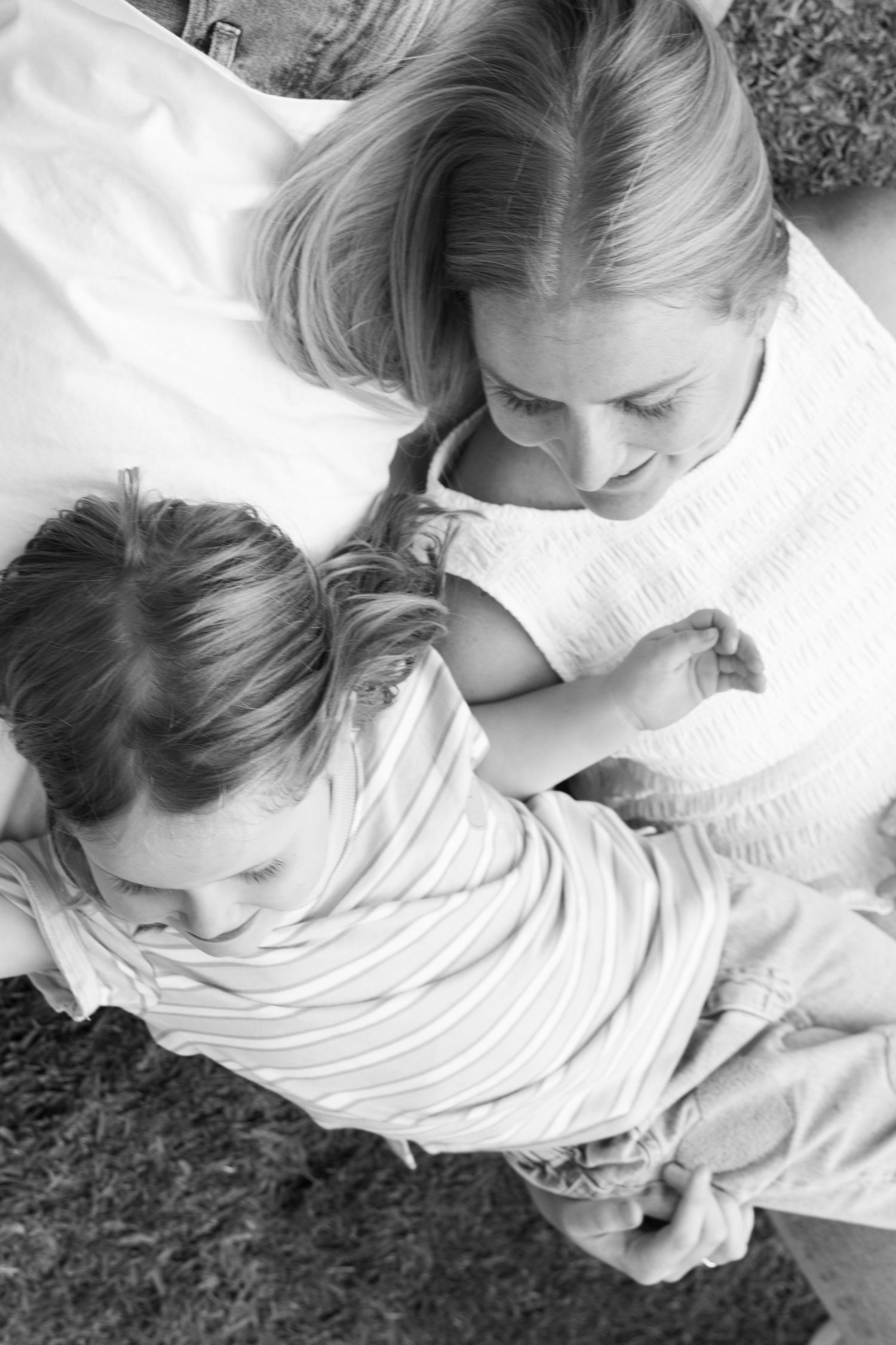 Black and white photo of a mother and child sitting together, sharing a tender moment outdoors.