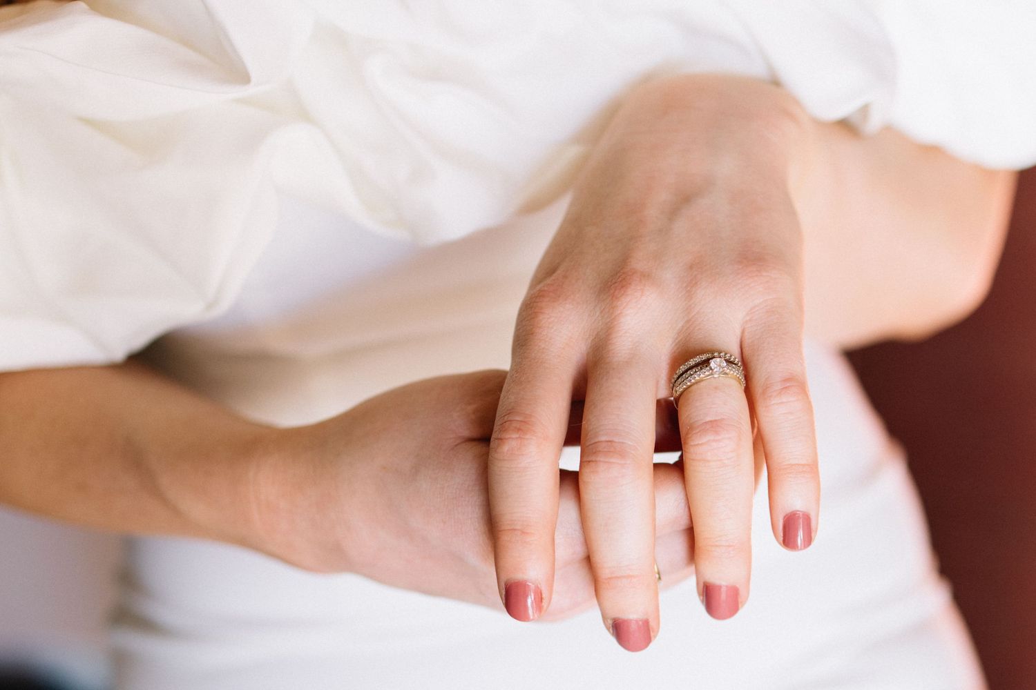 Close-up of a couple's hands showing wedding and engagement rings, symbolizing marriage and commitment.