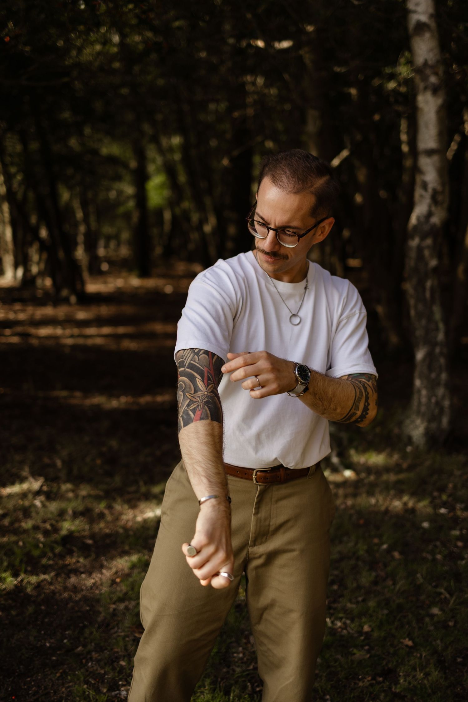 A sequence showing a person in a white t-shirt and khaki pants kneeling in a wooded outdoor setting.